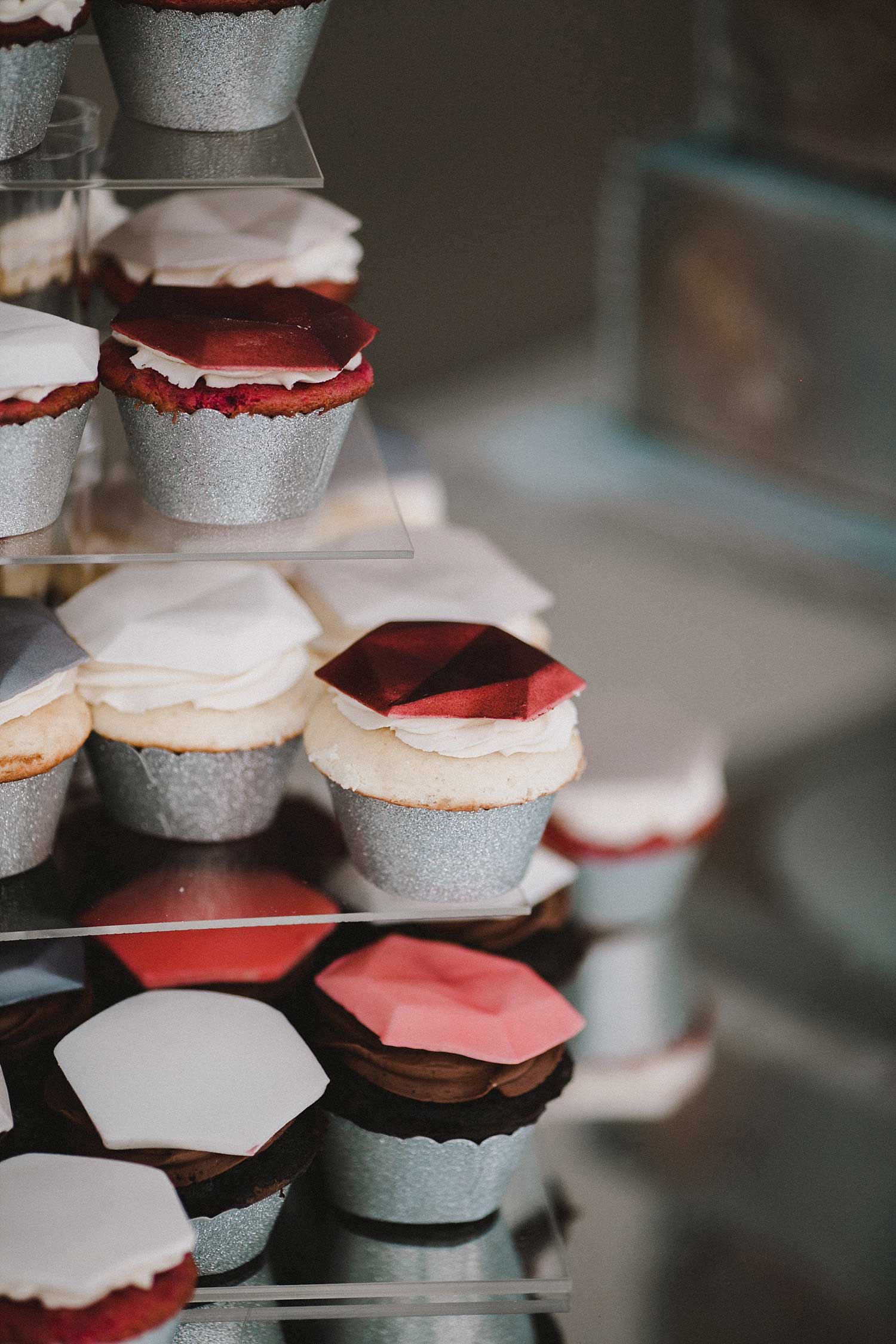 cupcakes with geometric shapes on top on a acrylic cake stand