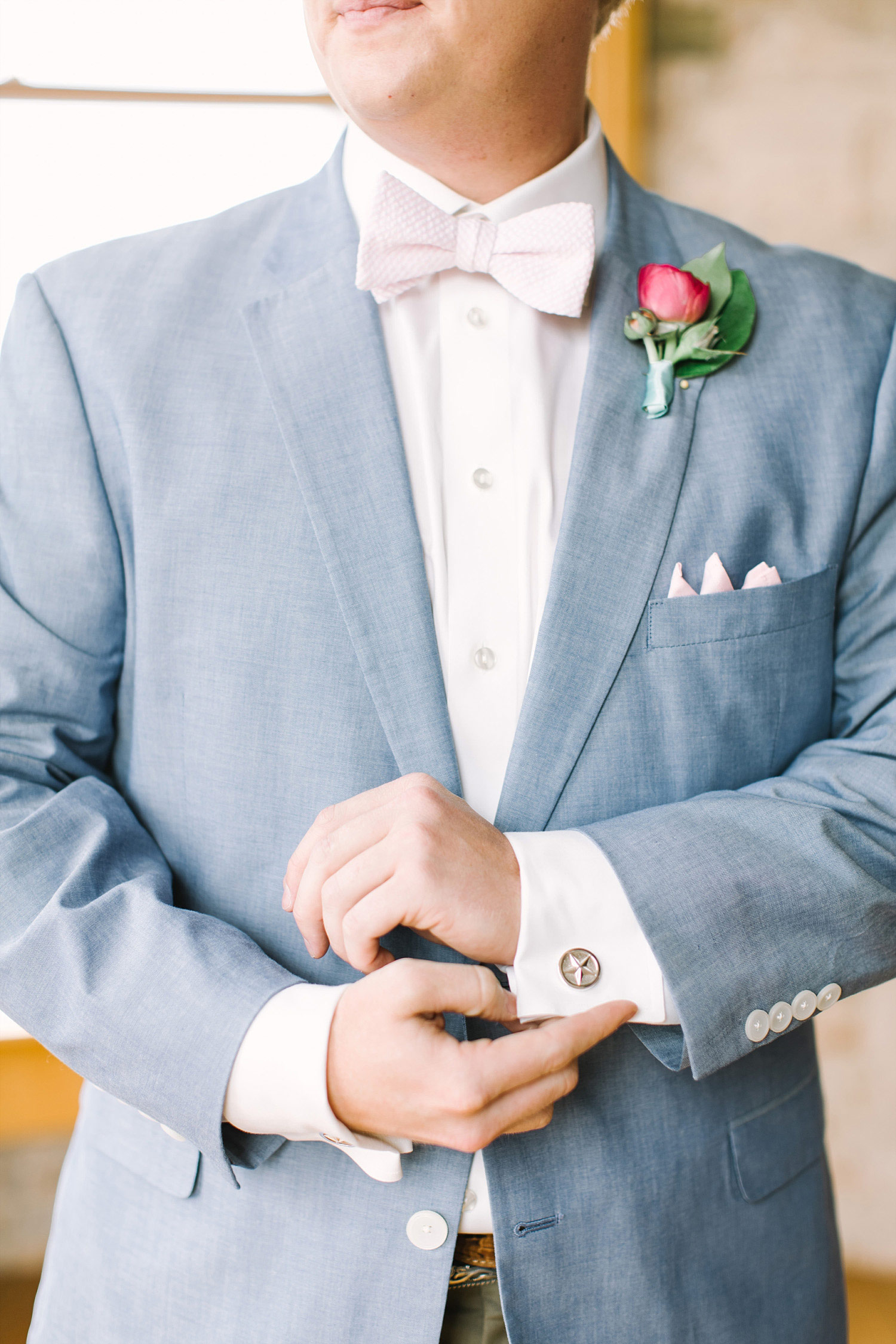 Groom where a light blue jacket, bowtie and pink boutonniere
