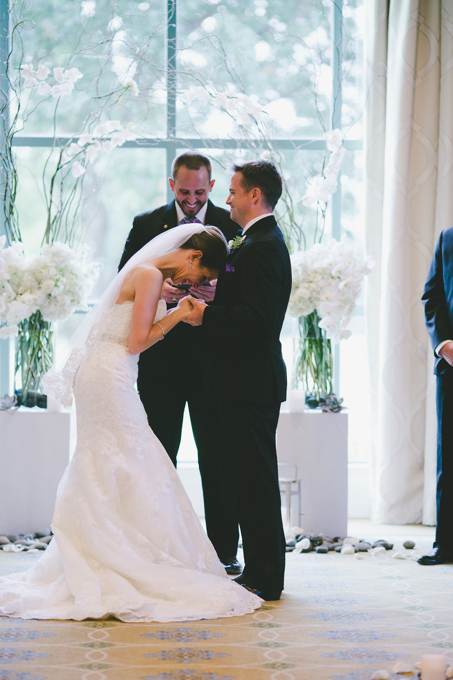 Bride laughing during ceremony at River Crest Country Club in front of white ceremony archway