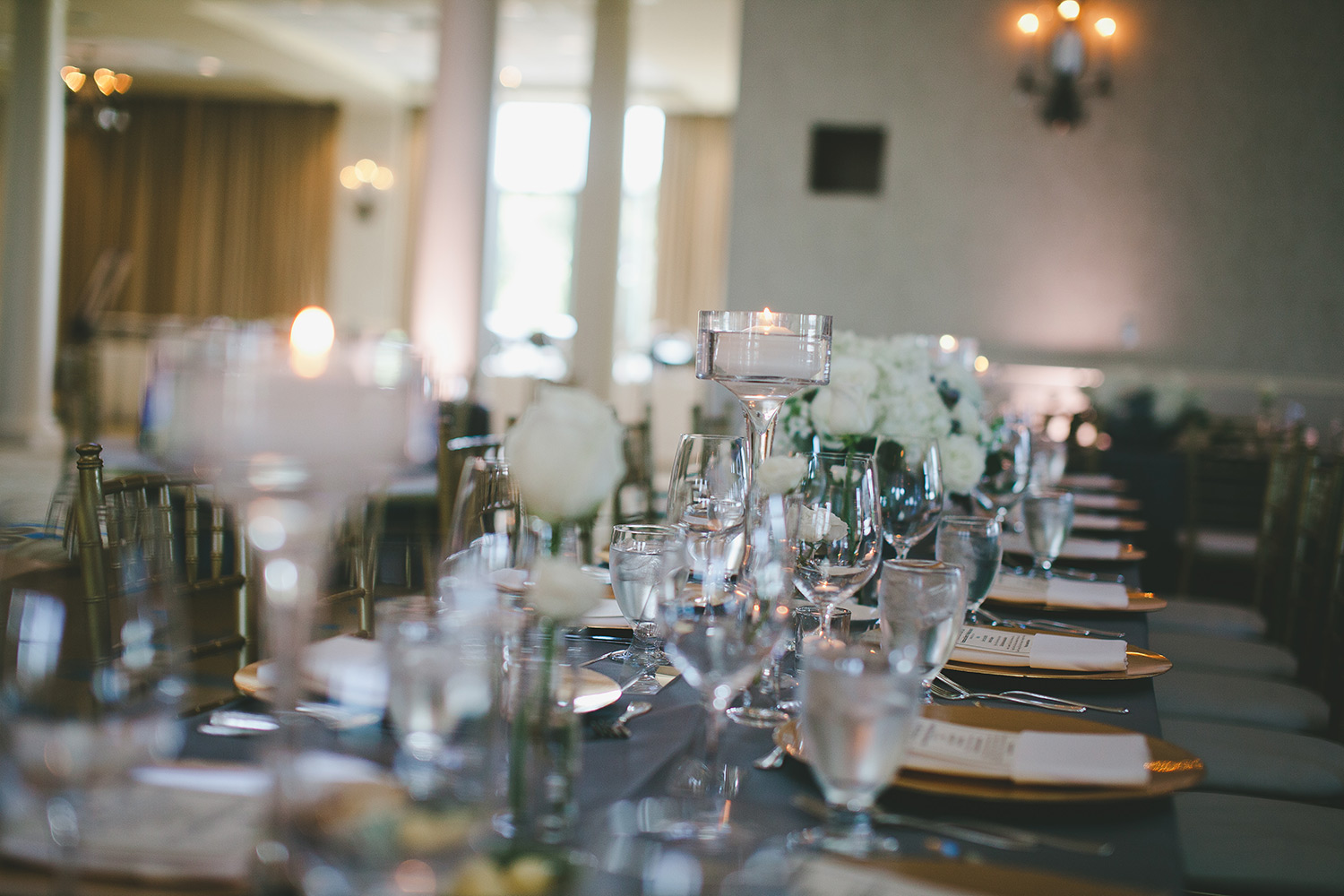 River Crest Country club grey linen with floating candles and gold chargers on table
