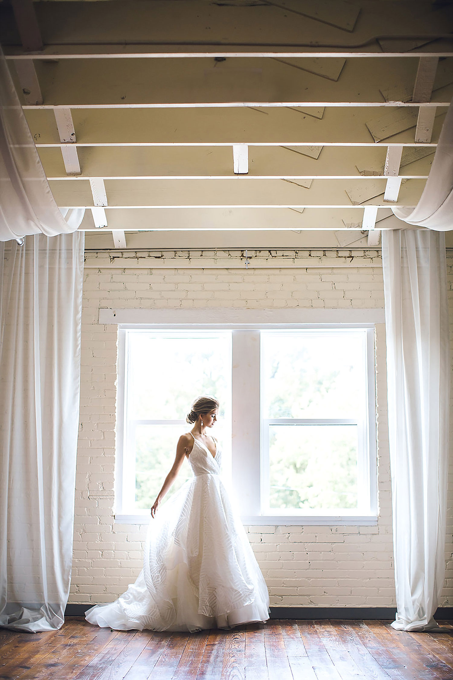 Brik Special Events Venue upstairs southern bride at window with white drapery