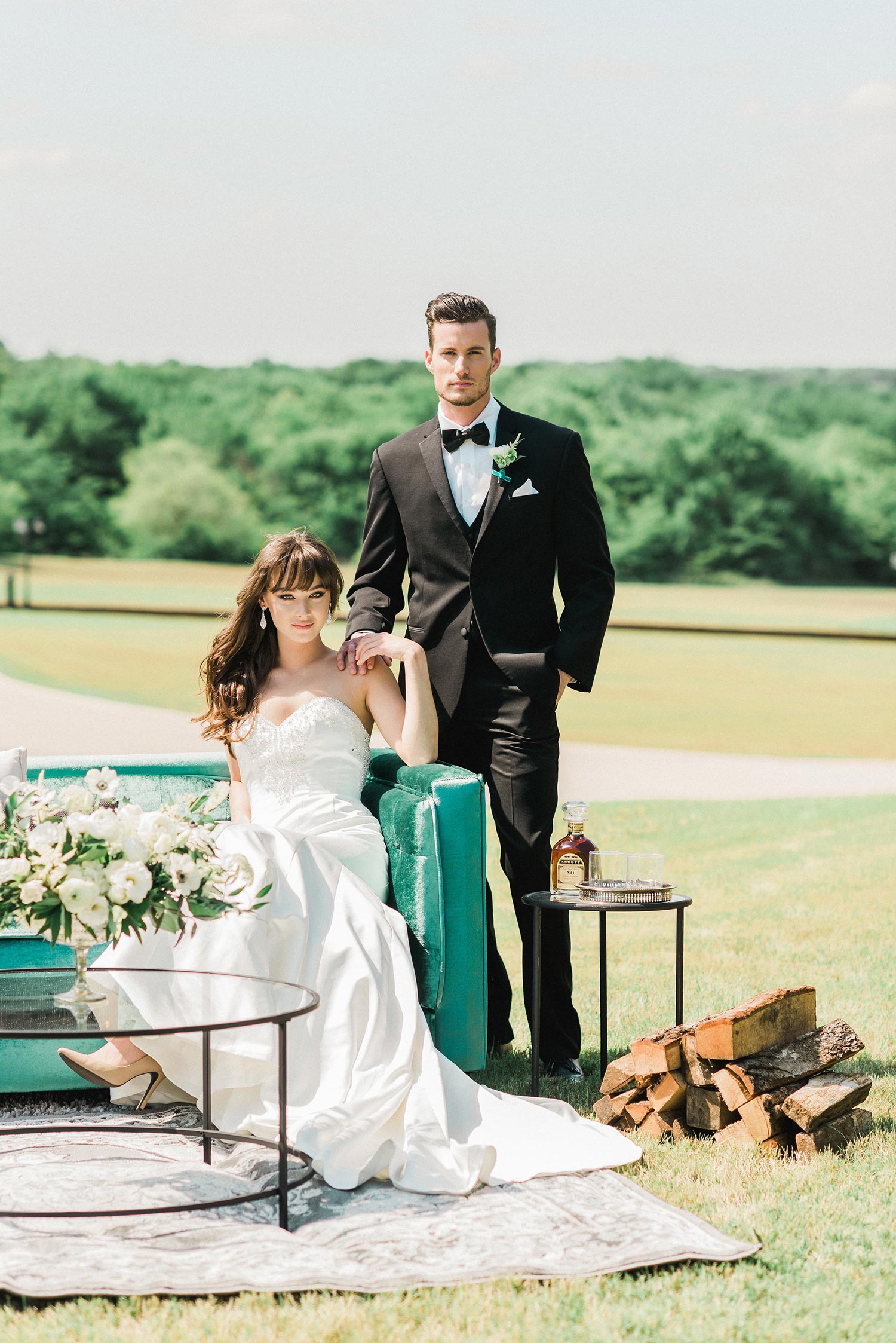 Bride and groom sitting on a emerald green sofa with firewood