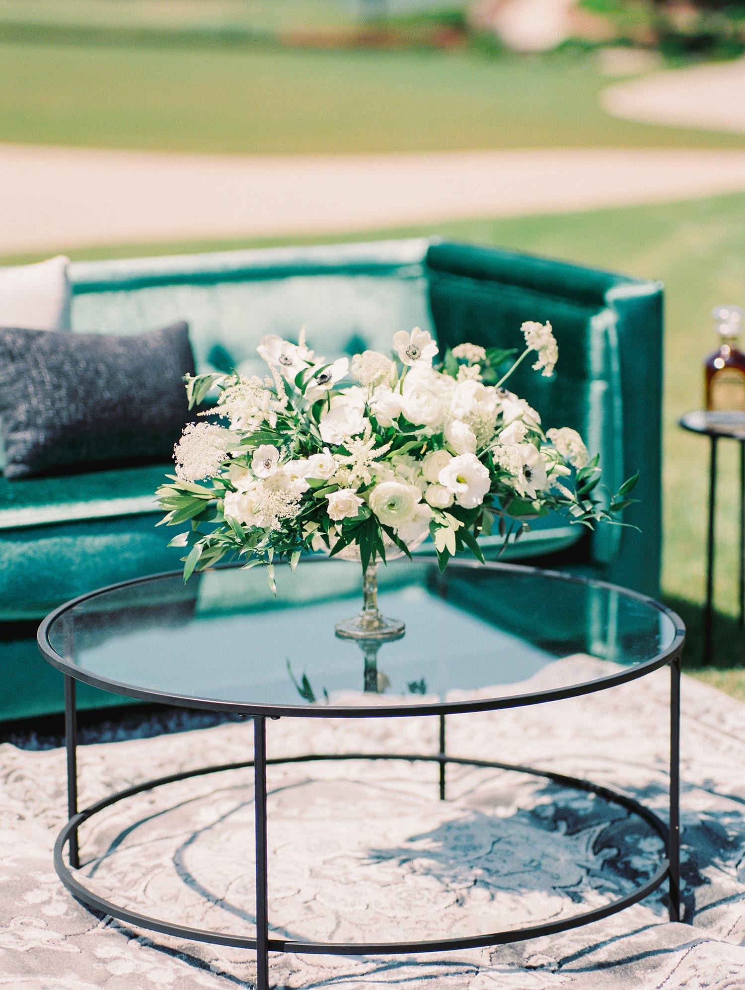 White flowers on a round coffee table at a outdoor wedding lounge