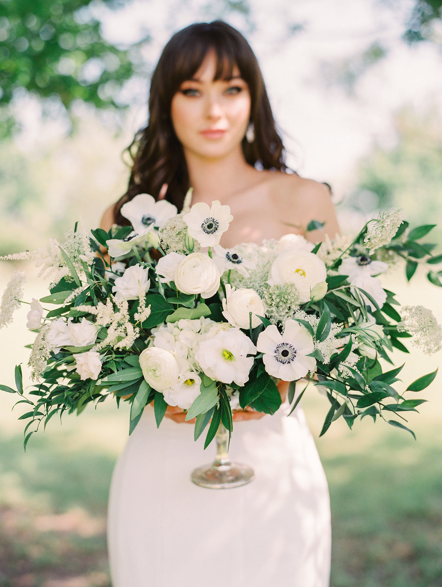 Bride holding white and green flowers in a silver vase