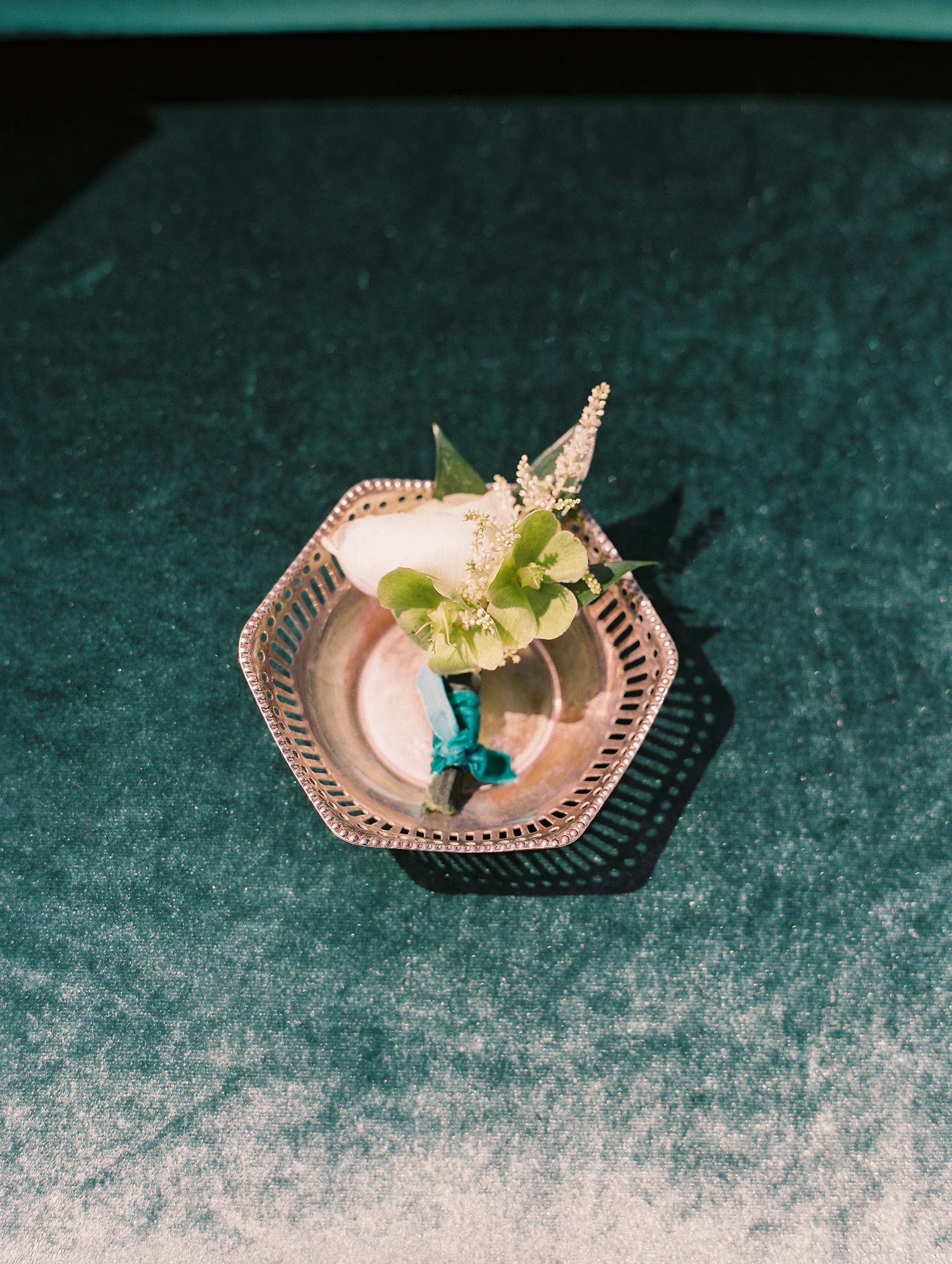 Groom's white boutonniere with a velvet green tie