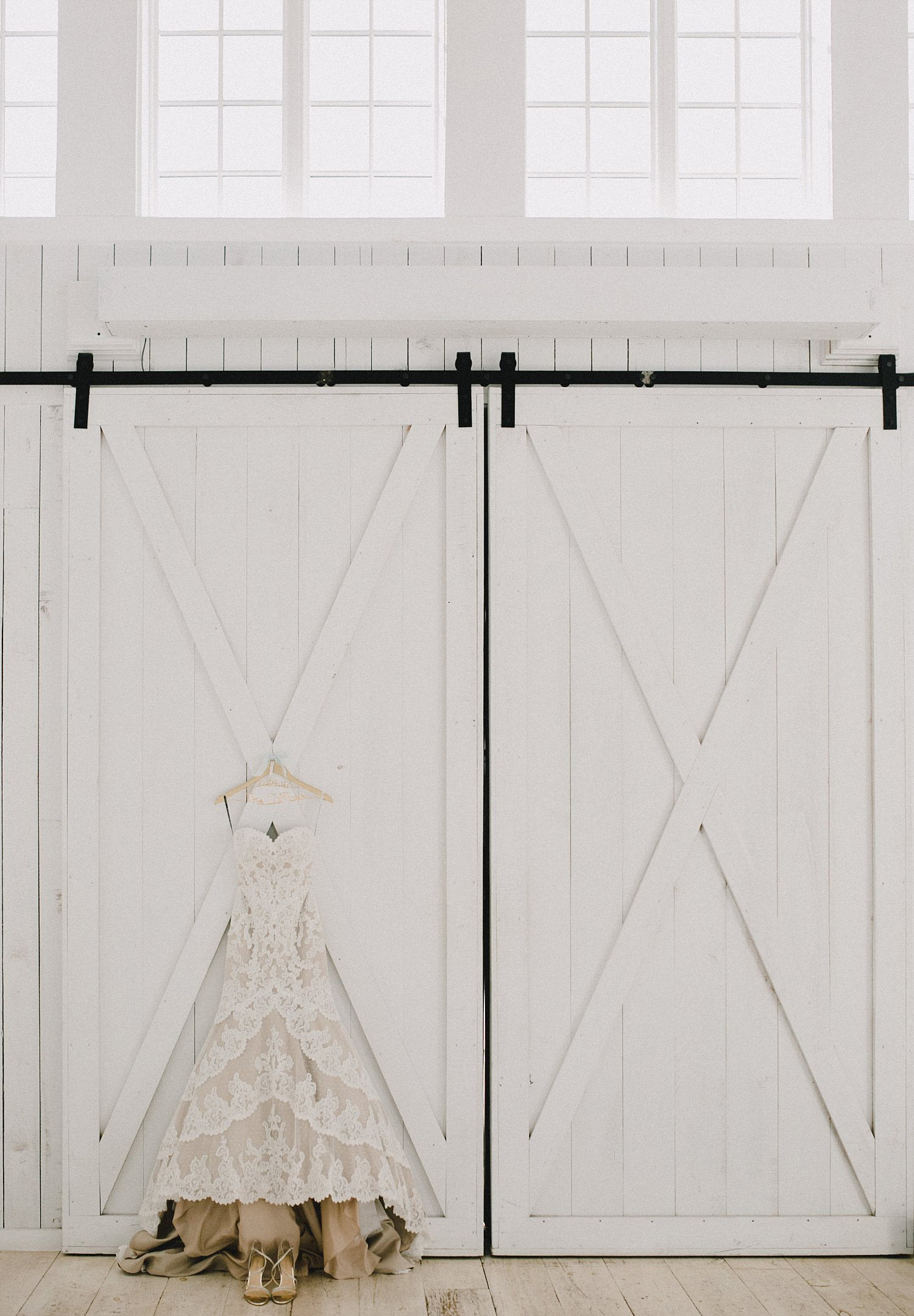 White Sparrow Barn wedding dress hanging on white barn doors with windows above