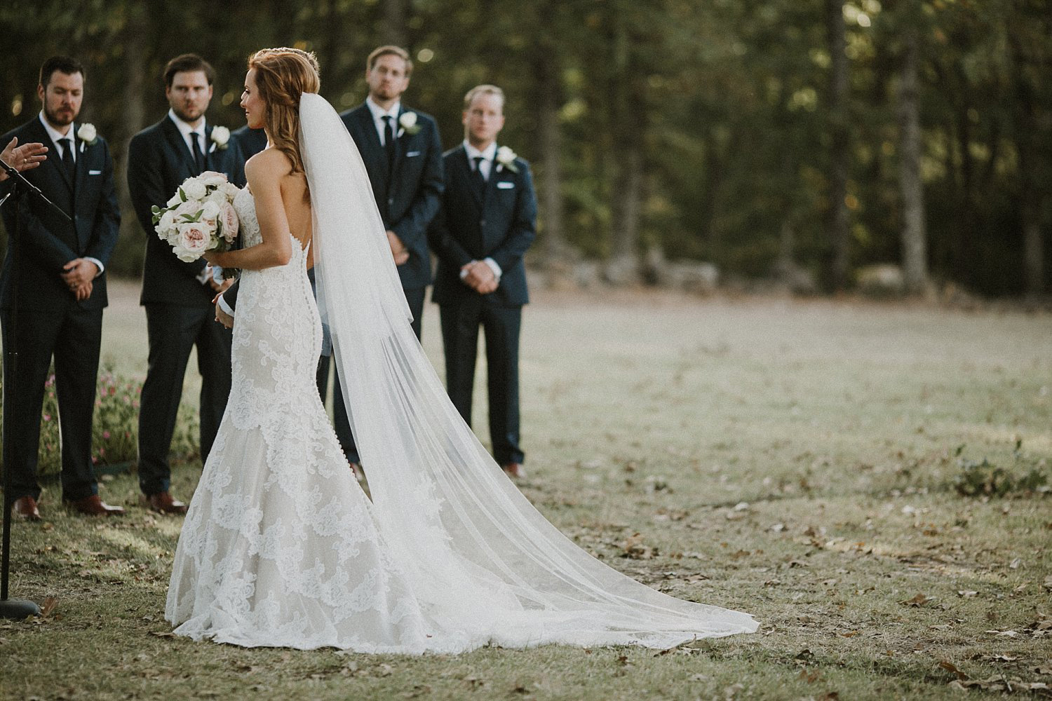 Dallas Cowboy Cheerleader bride at White Sparrow Barn outdoor ceremony with long cathedral veil