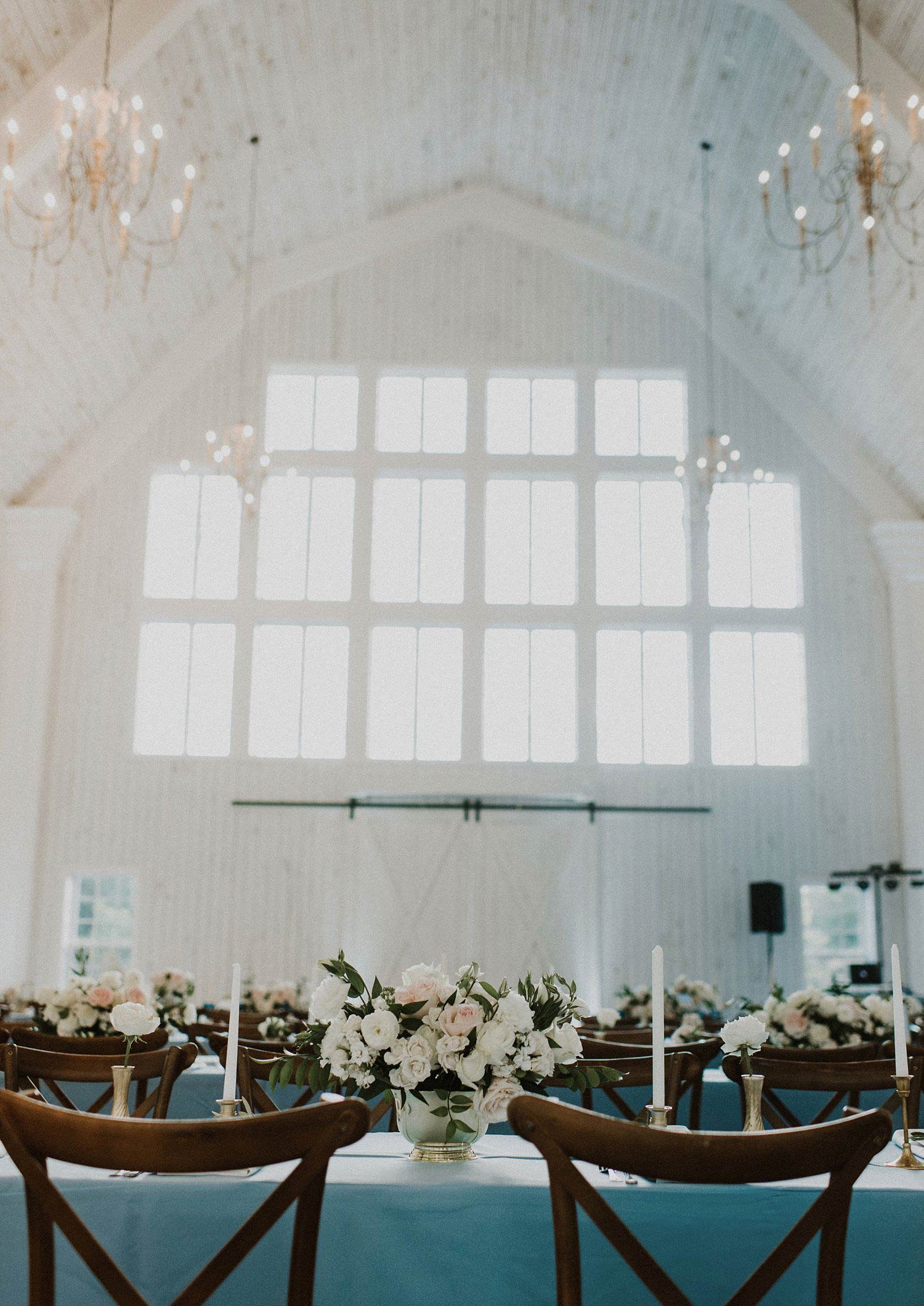 White Sparrow Barn wedding reception dusty blue linens and white and blush flowers in gold vase
