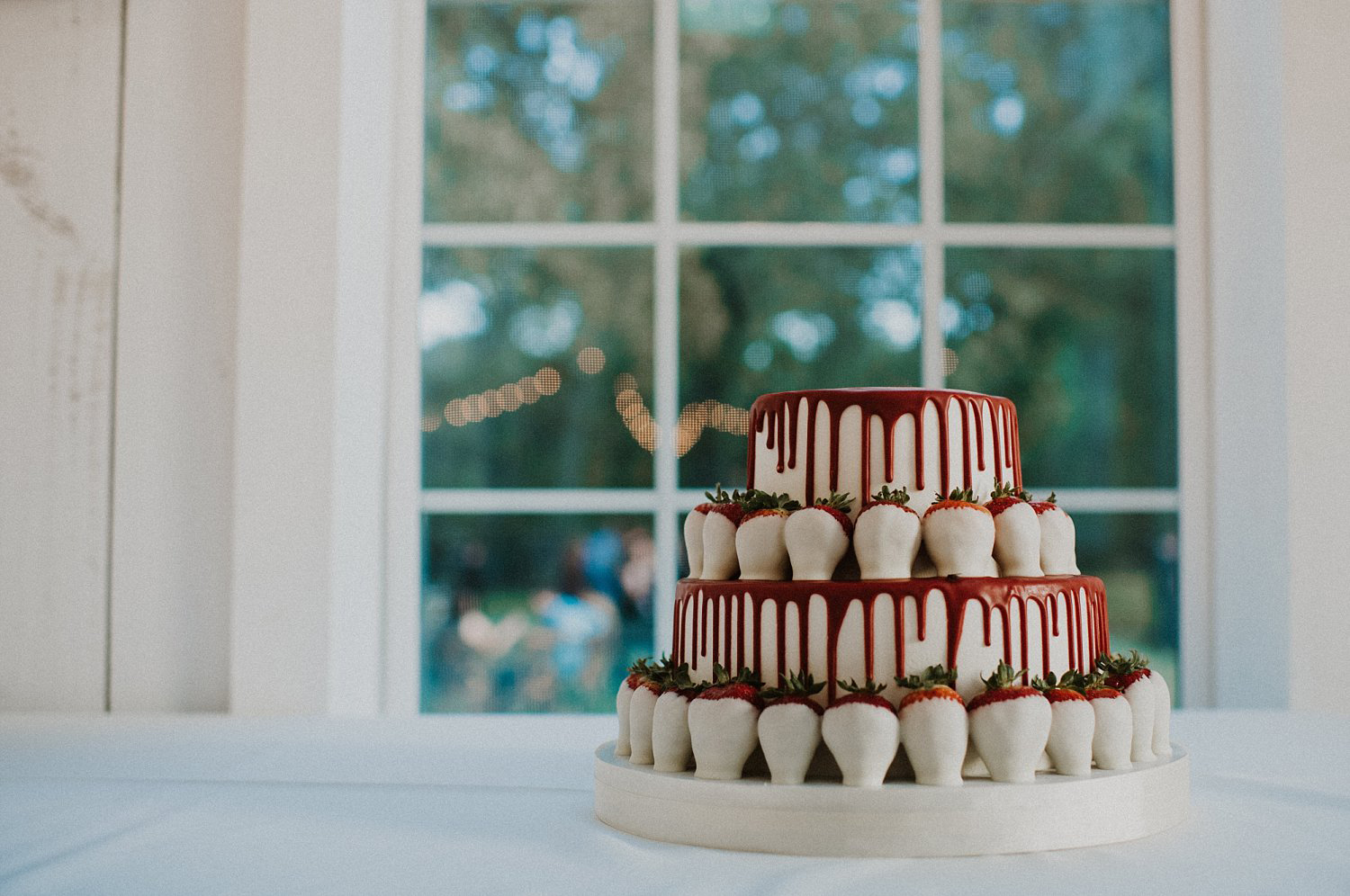 White and red groom drip cake with white chocolate strawberries