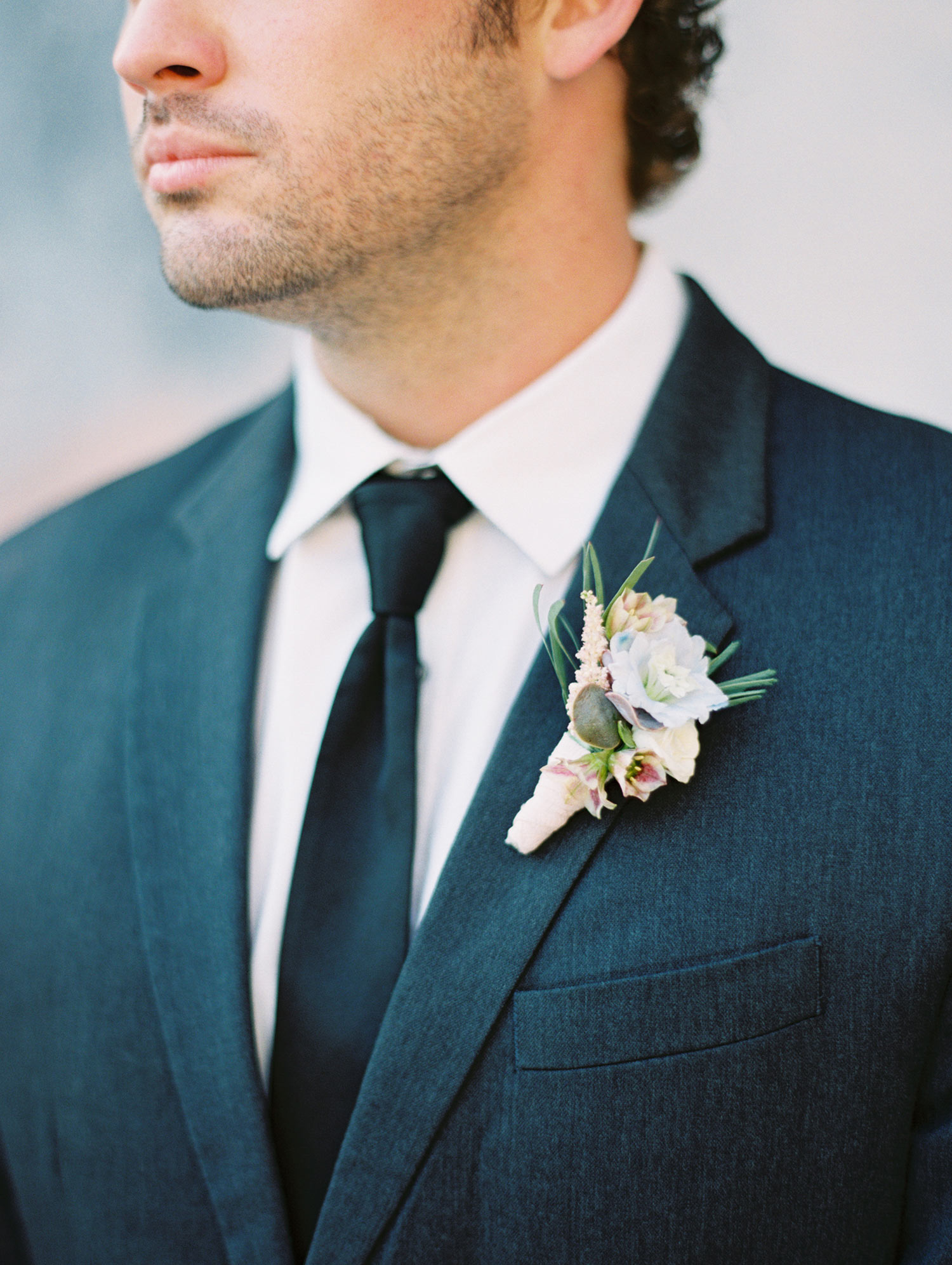 Groom in black tux with a lavender boutinere