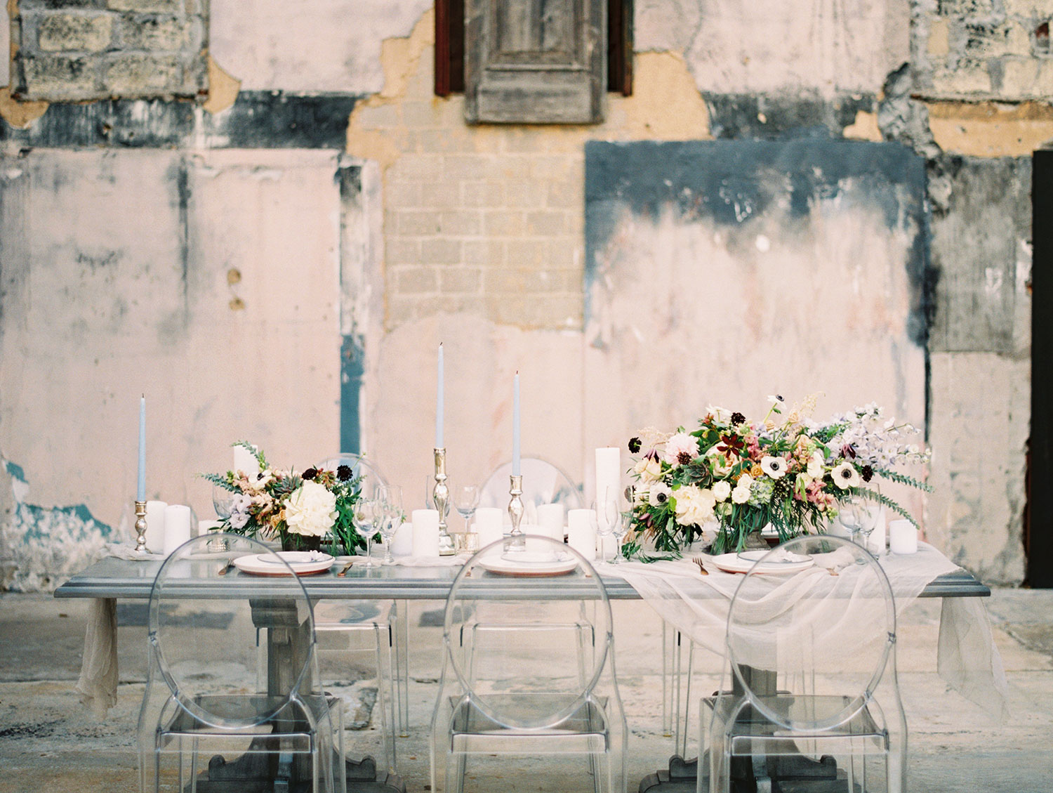 Grey farm table with a white runner and moody flowers