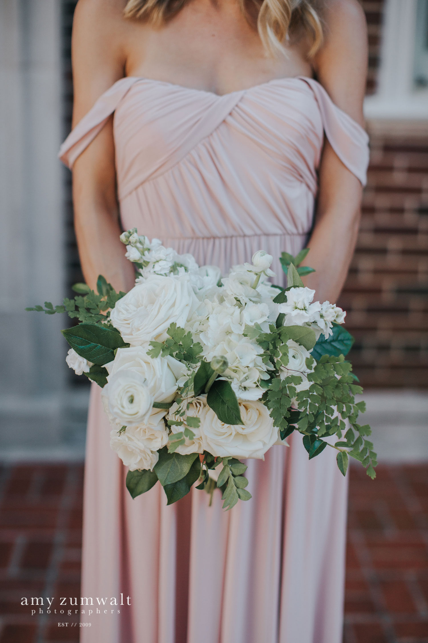 Bridesmaid in mauve bridesmaid dress holding a white and green bouquet