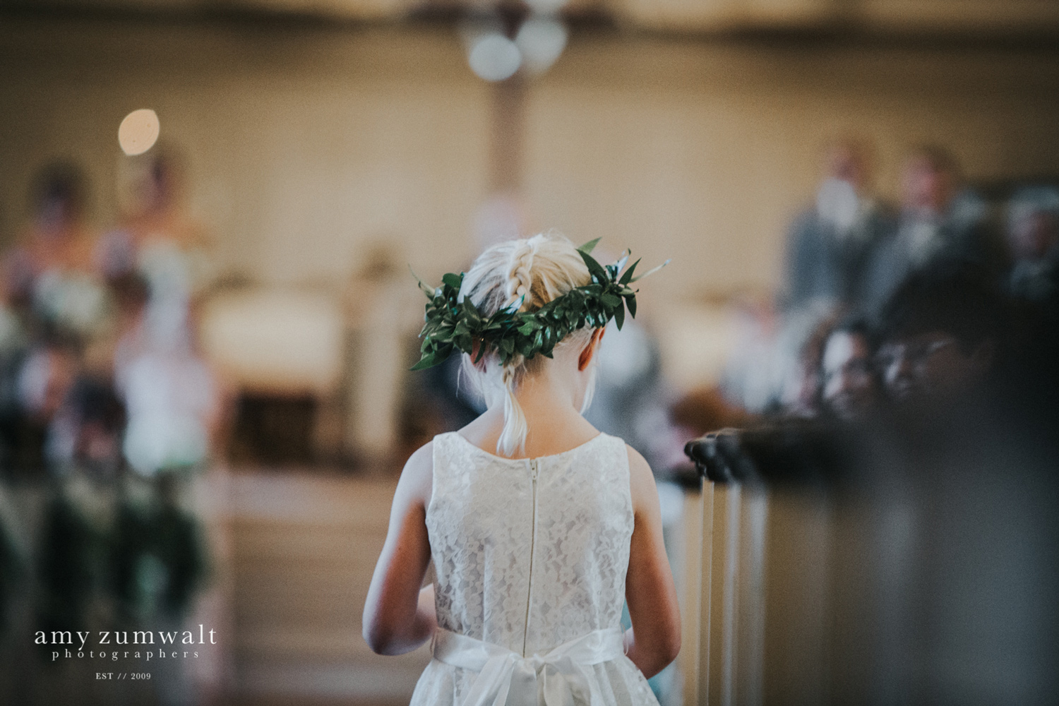 Flower girl with greenery floral crown walking down the aisle