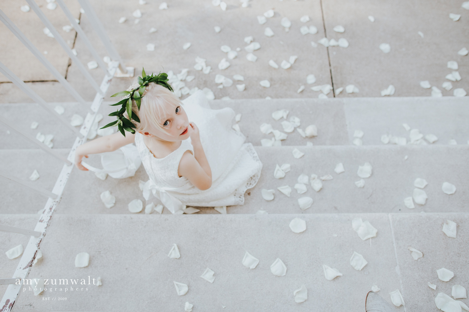 Flower girl sitting in white pedals