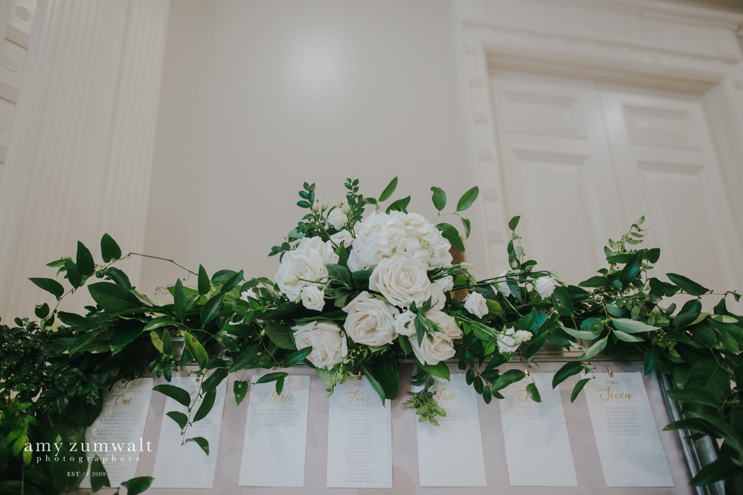 Green garland with white flowers on seating chart