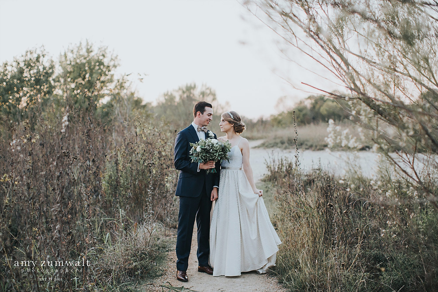 Bride and groom at Trinity River Audubon Center in the fall with tall brown grass