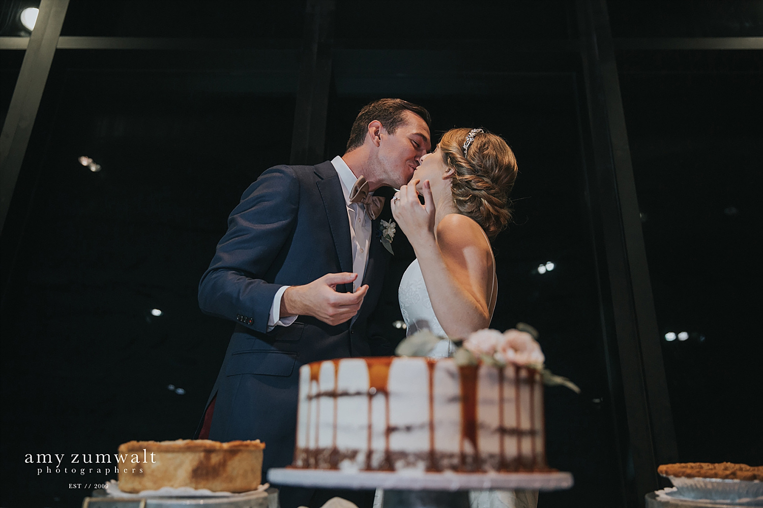 Bride and groom kissing with caramel drip cake at the Trinity River Audubon Center in Dallas TX