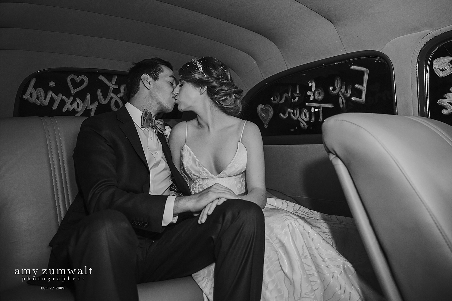 Bride and groom kissing in the exit car at a dallas wedding