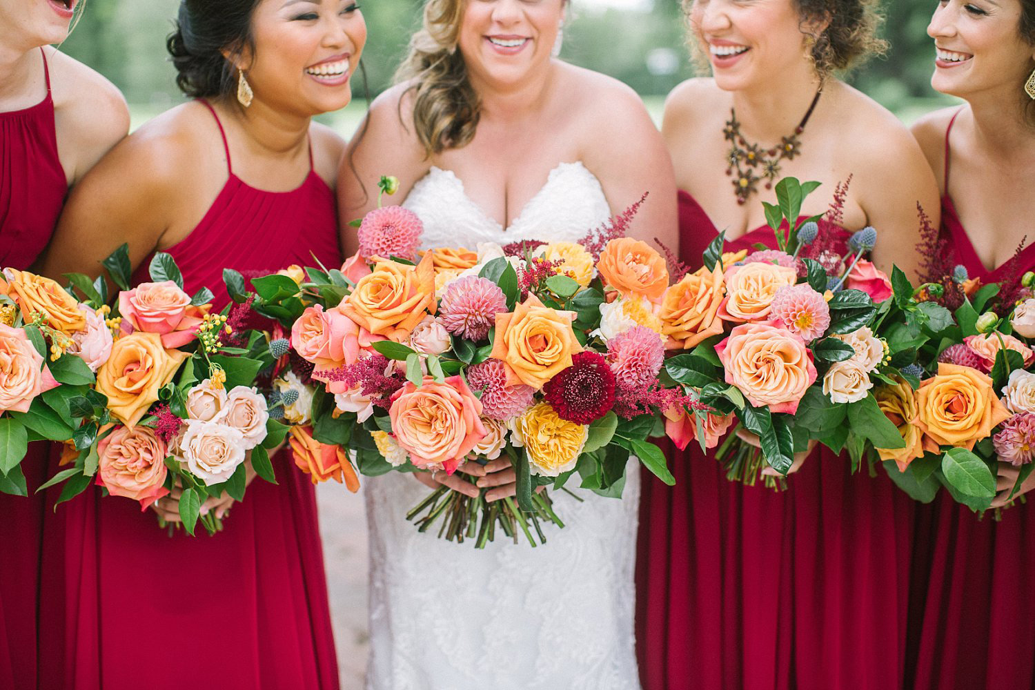 Bridesmaids holding orange coral and apricot bouquets