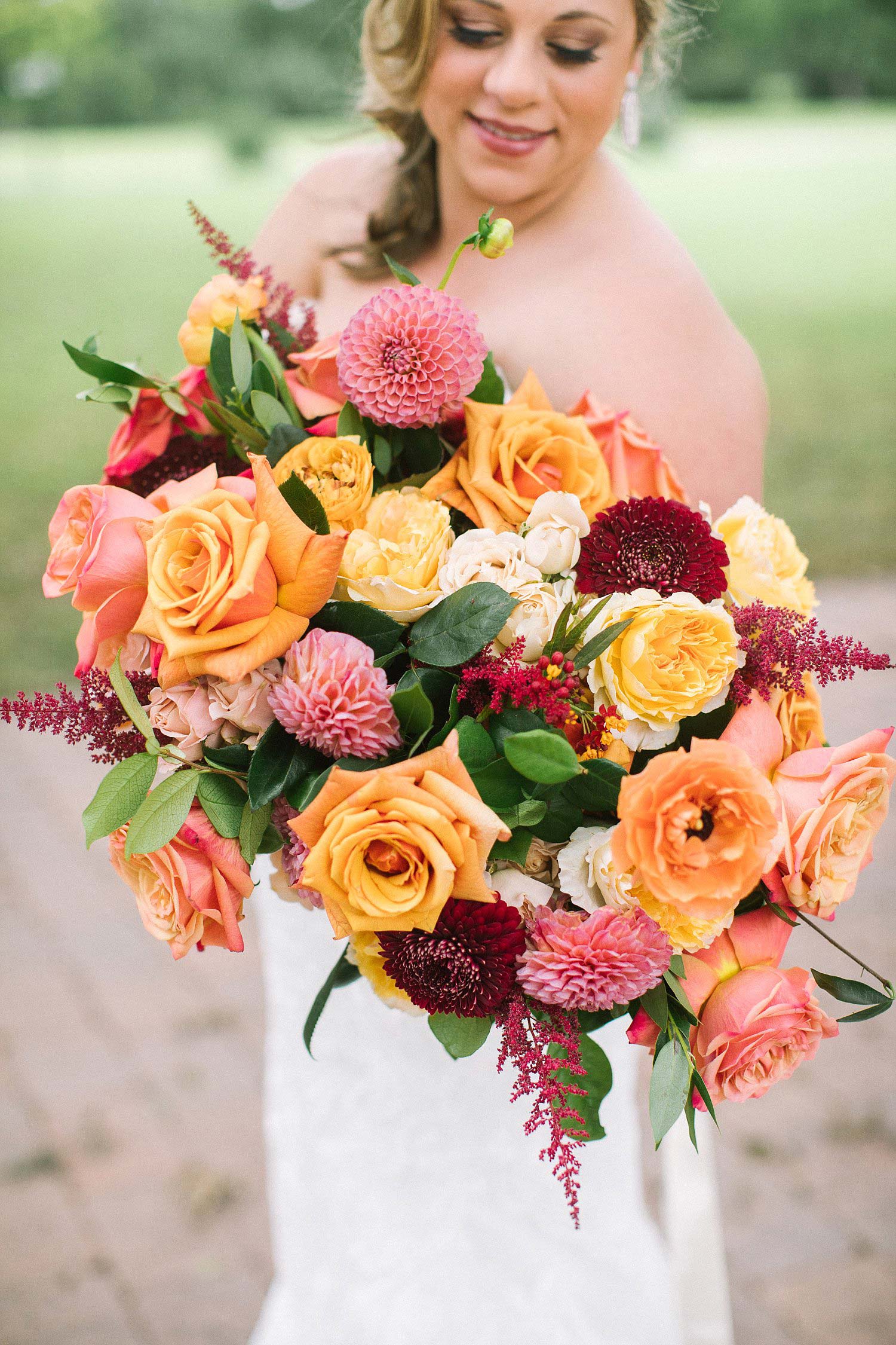 Bride holding apricot coral yellow and burgundy bridal bouquet