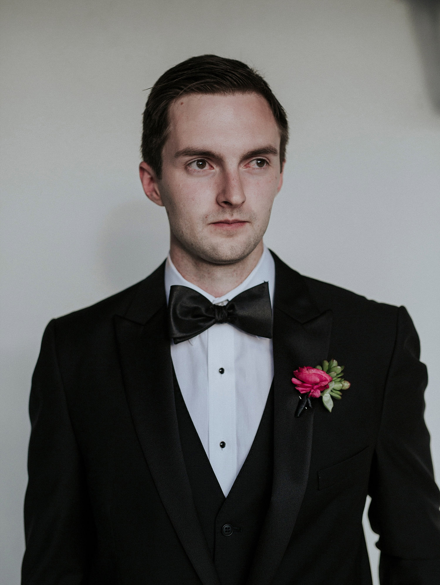 Groom wearing a black tux and pink boutonniere
