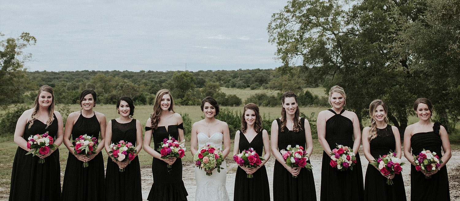 bridesmaids in long black dresses holding pink bouquets