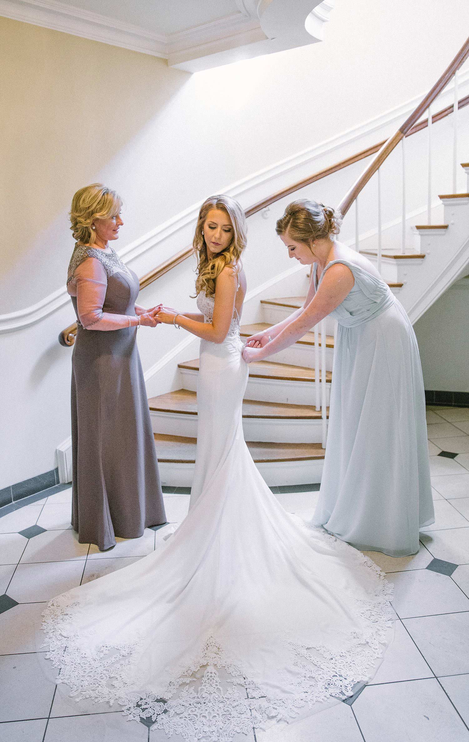 Bride and maid of honor putting on brides dress