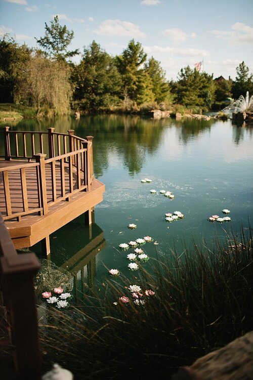 Floating lillies and candles in water at a wedding ceremony