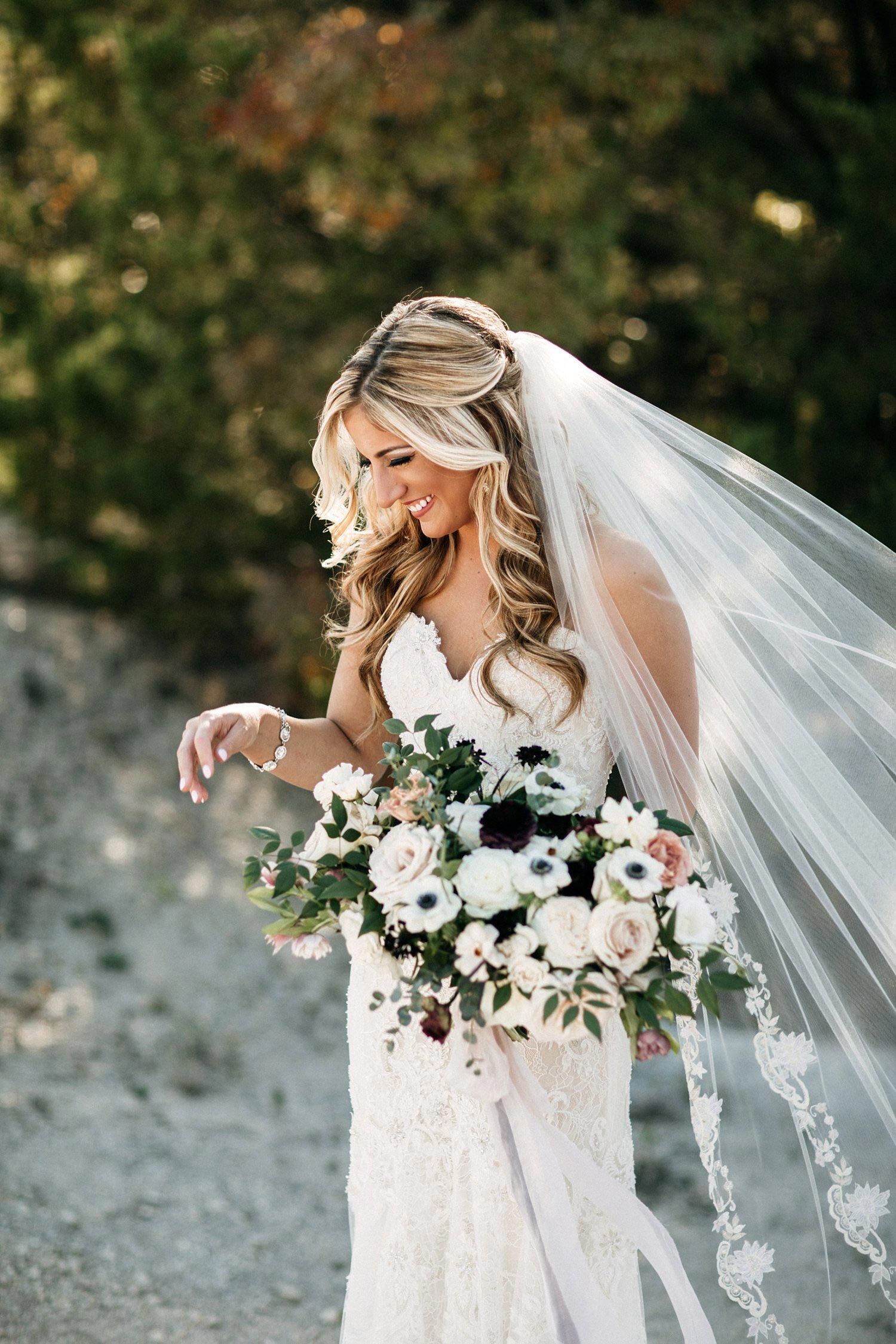Bride holding moody organic bridal bouquet with black &amp; white flowers