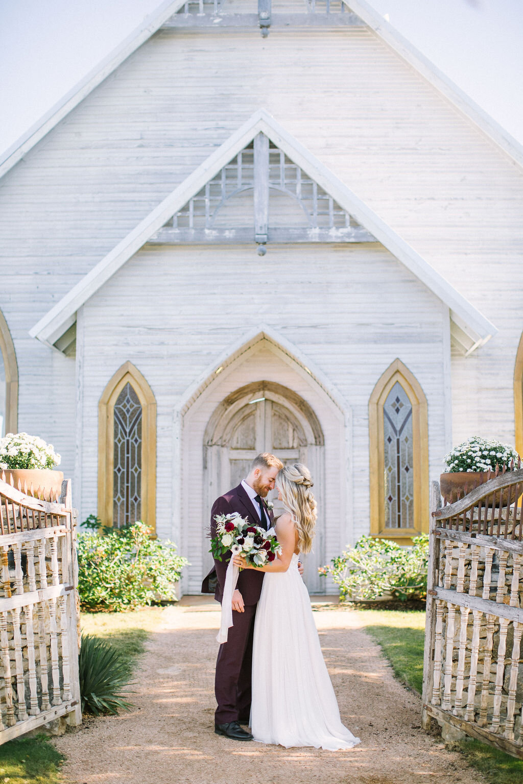 bride and groom in front of a whtie chapel at Brooks at Weatherford wedding