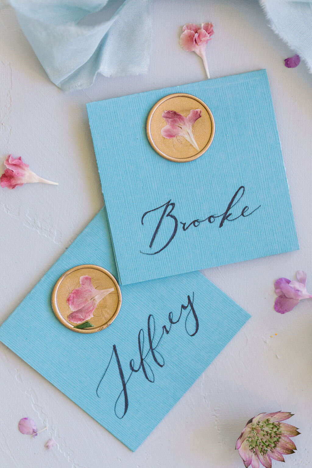 Blue escort cards with pink pressed flowers &amp; gold wax seals
