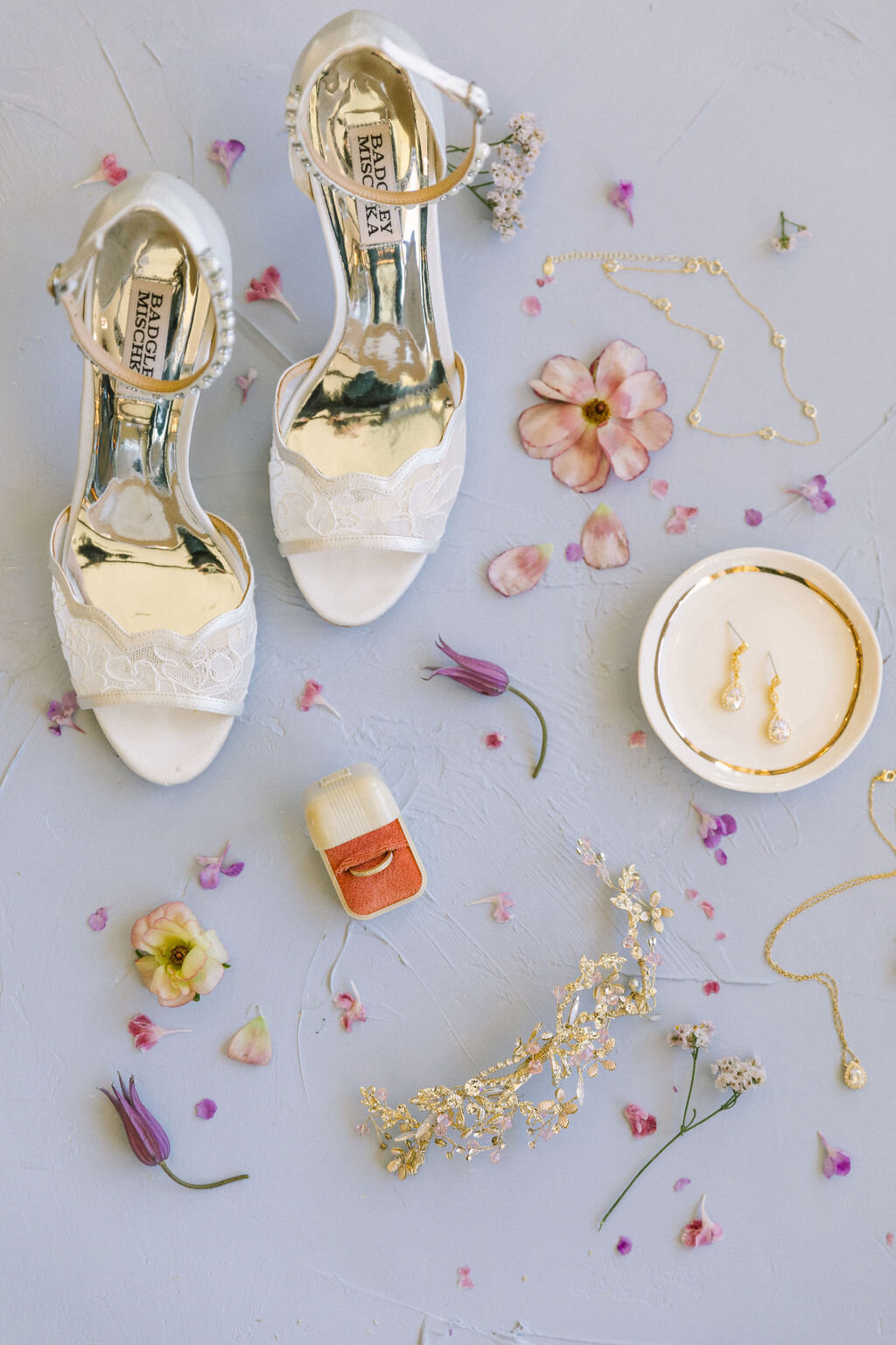 Bridal detail flat lay with a orange ring box and white shoes on a purple backdrop