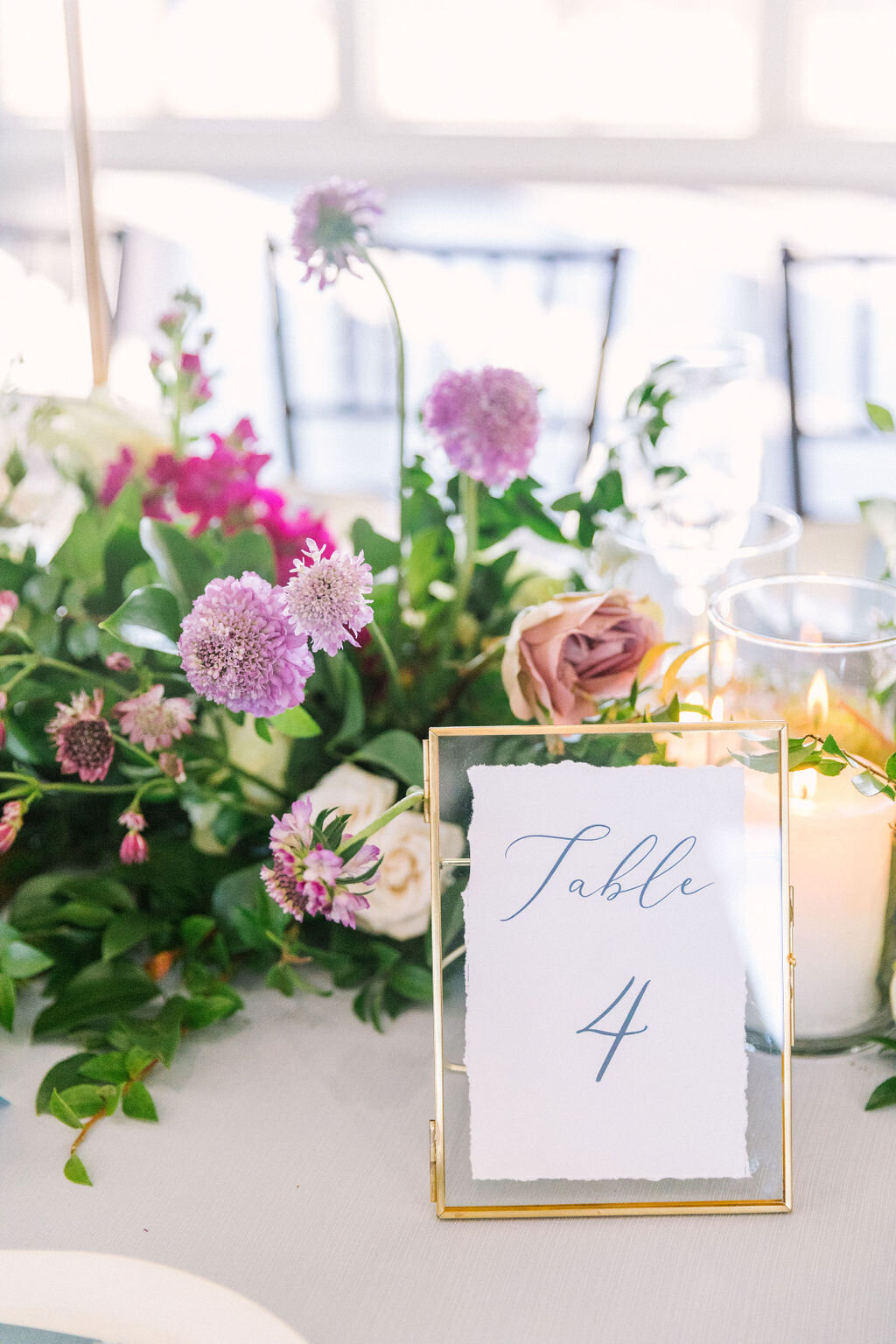 Gold float frame table number with a purple flower centerpiece