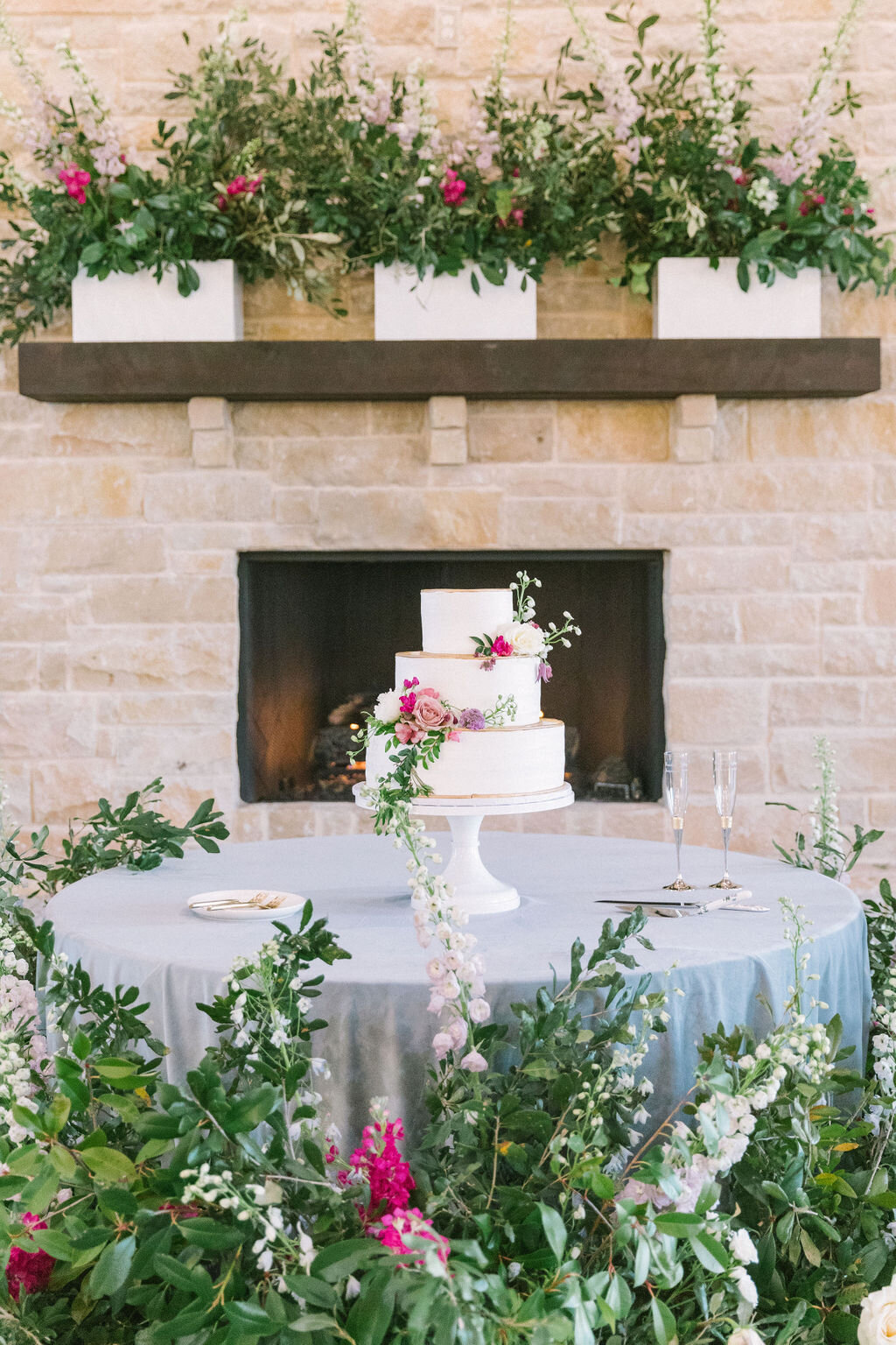 Cake on a blue linen with flowers around the base of the table