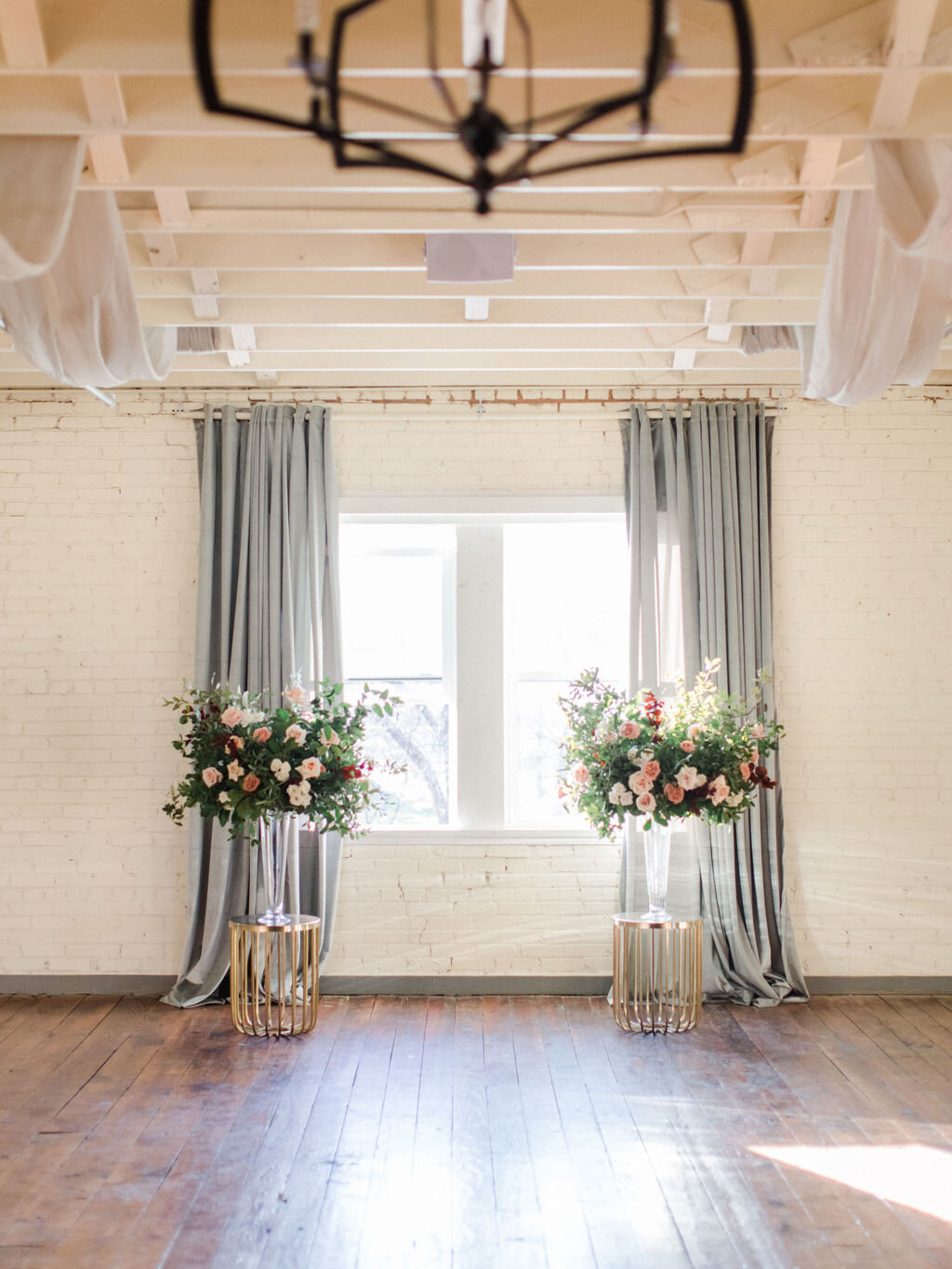 Ceremony at Brik Venue in Fort Worth Texas with two large floral arrangements