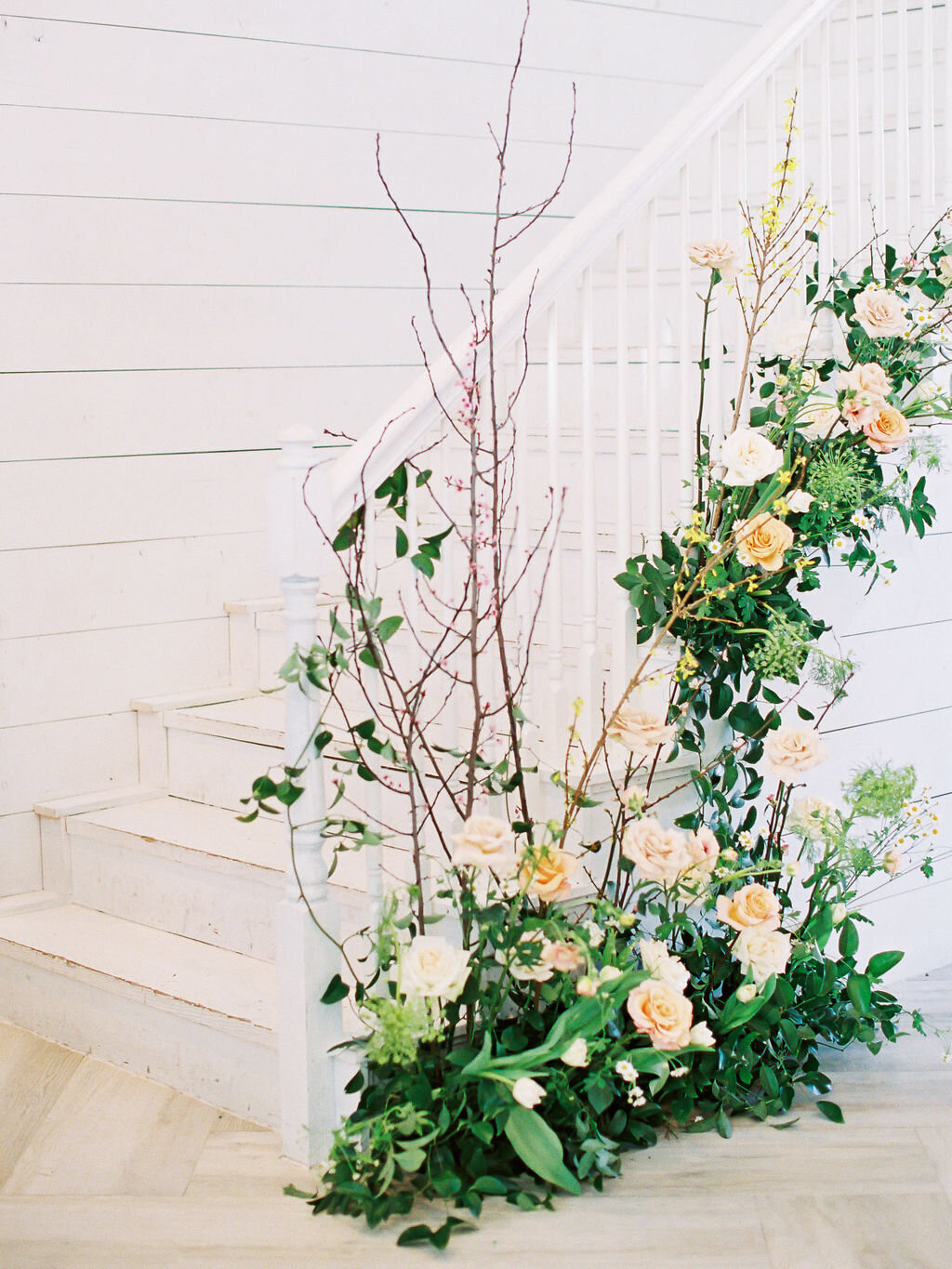 Staircase flower installation in the Nest at Ruth Farms lobby with yellow &amp; white flowers.