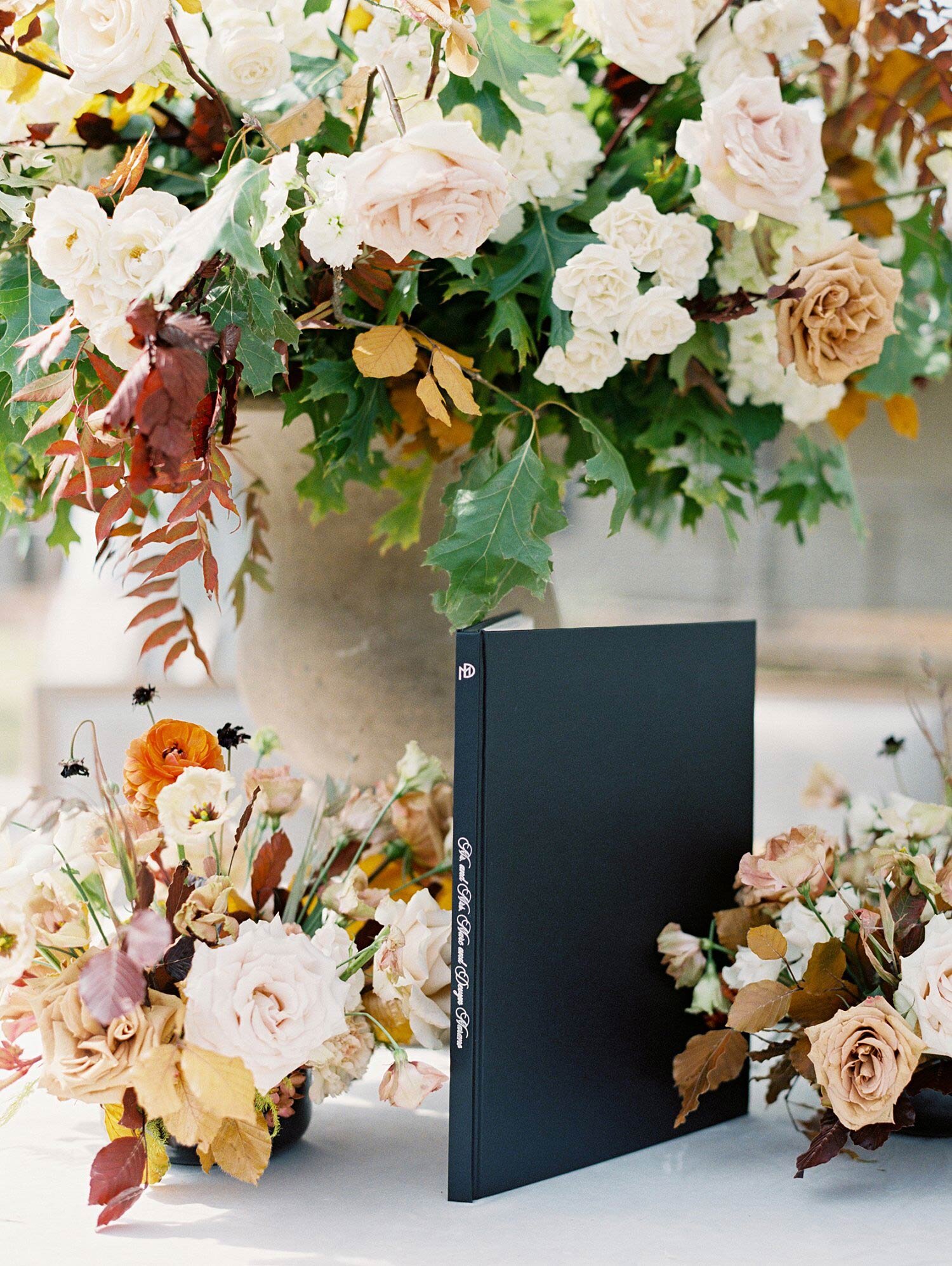 Black guest book with white text and fall flowers in the background