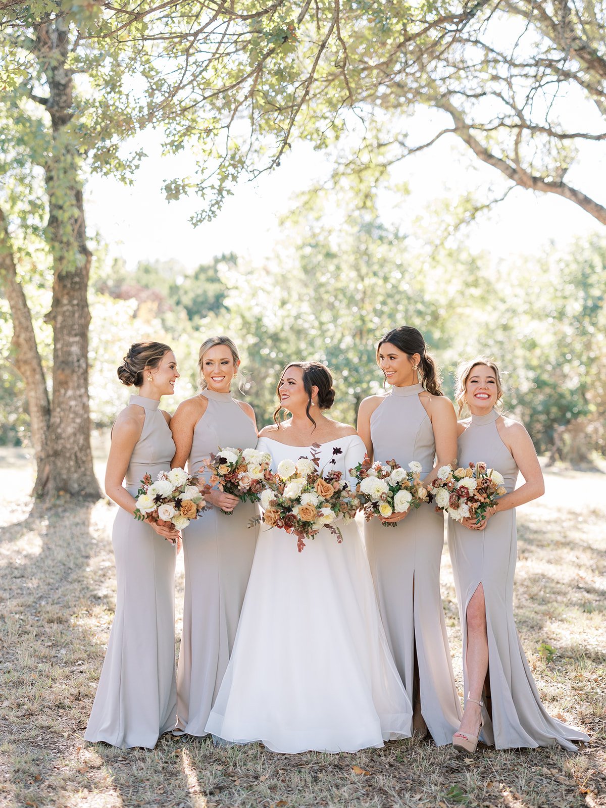 Bridesmaids in long grey dresses with red bouquets at Texas Outdoor Wedding