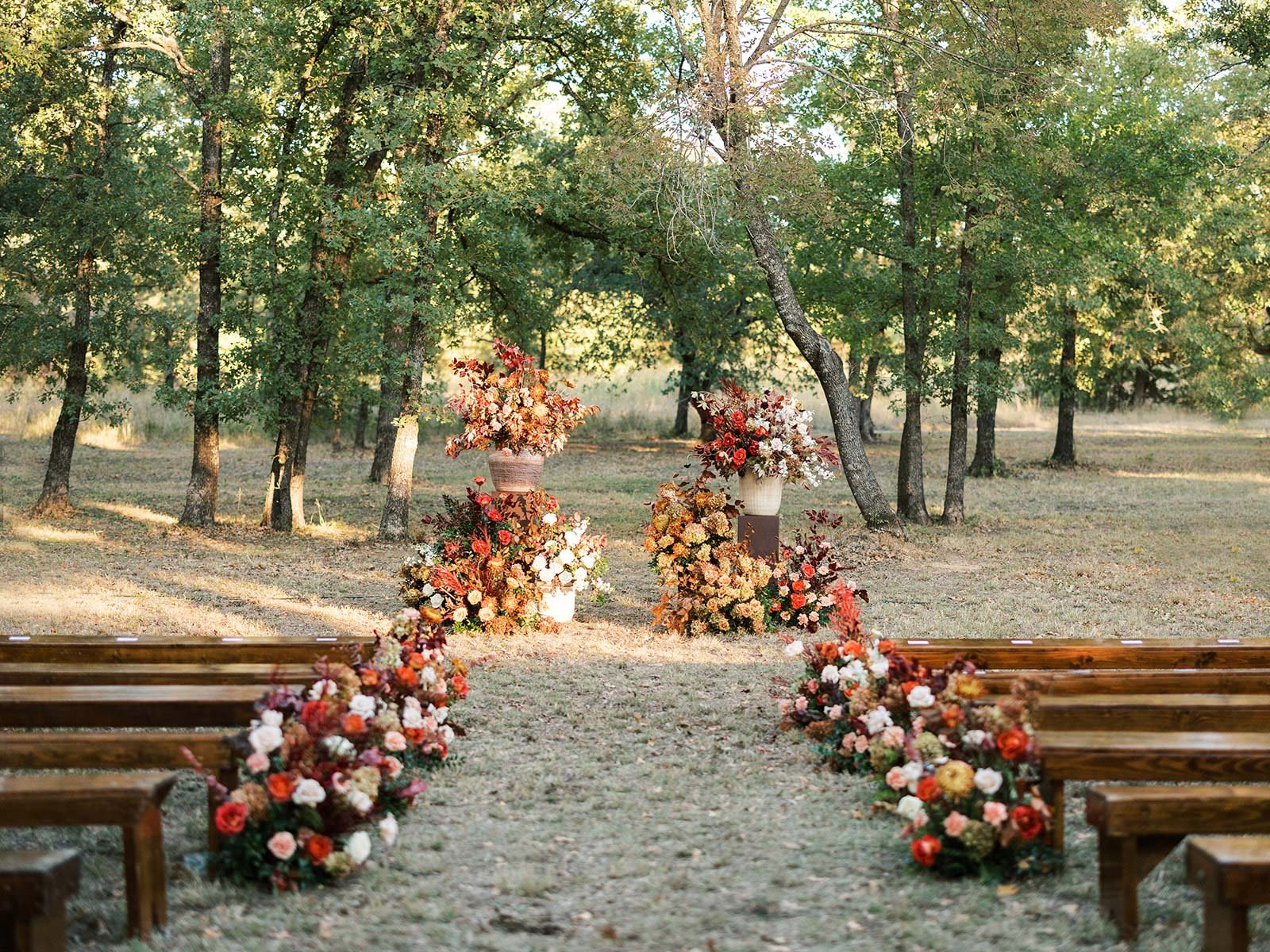 Ranch wedding ceremony with red flowers and brown benches | Designed and Planned by Shannon Rose Events