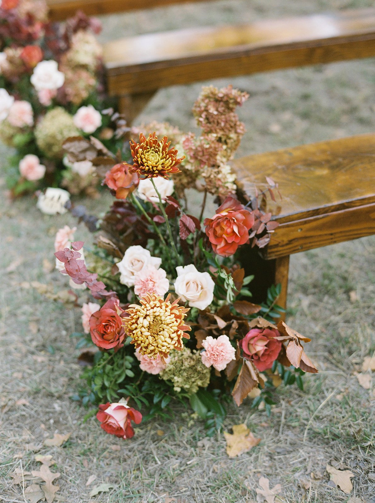 Red Orange gold and pink flowers on Ceremony Aisle at outdoor Ranch wedding wedding