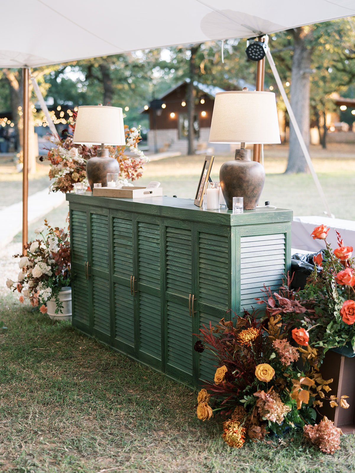 Green bar facade with large brown lamps at tented wedding in Glen Rose Texas