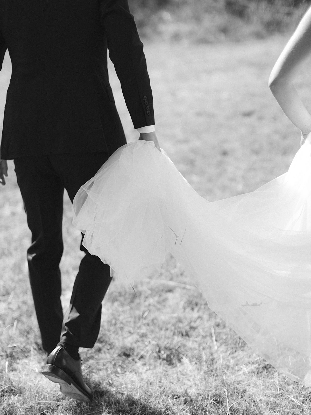 Groom holding bride's wedding dress in black and white