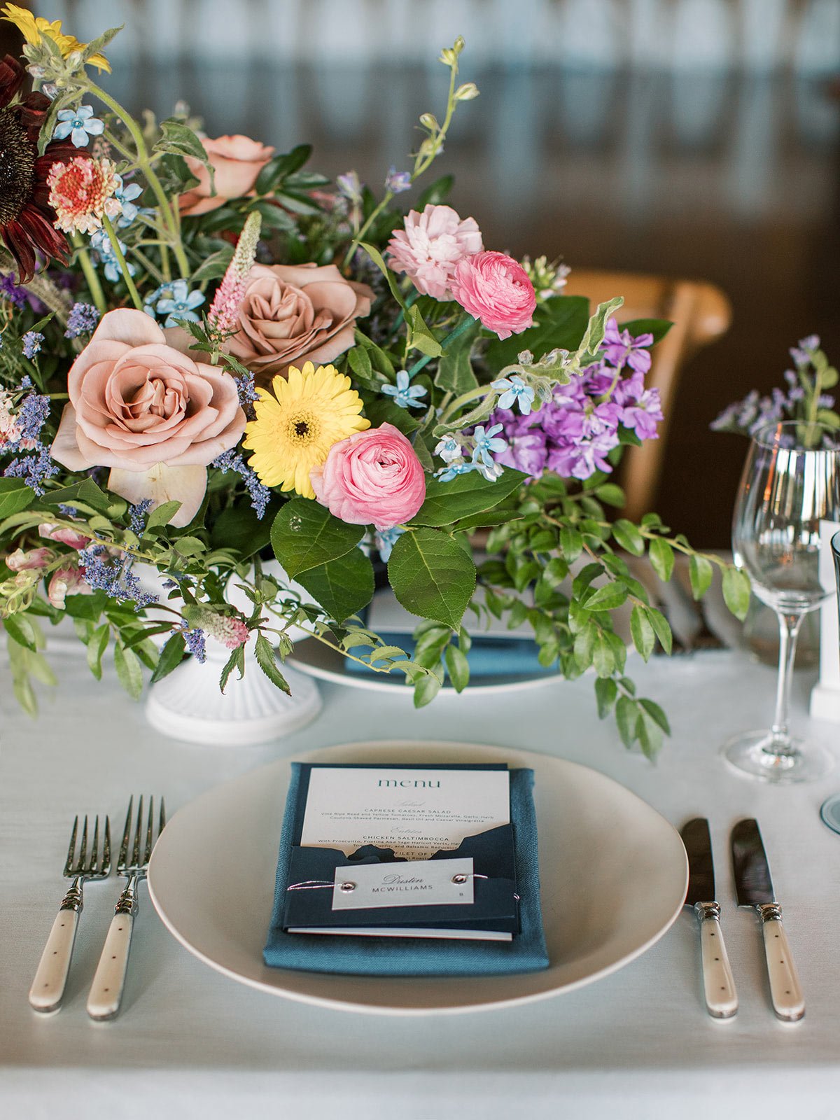 Montana wedding place setting with blue menu and colorful wildflower wedding flowers designed by Shannon rose events