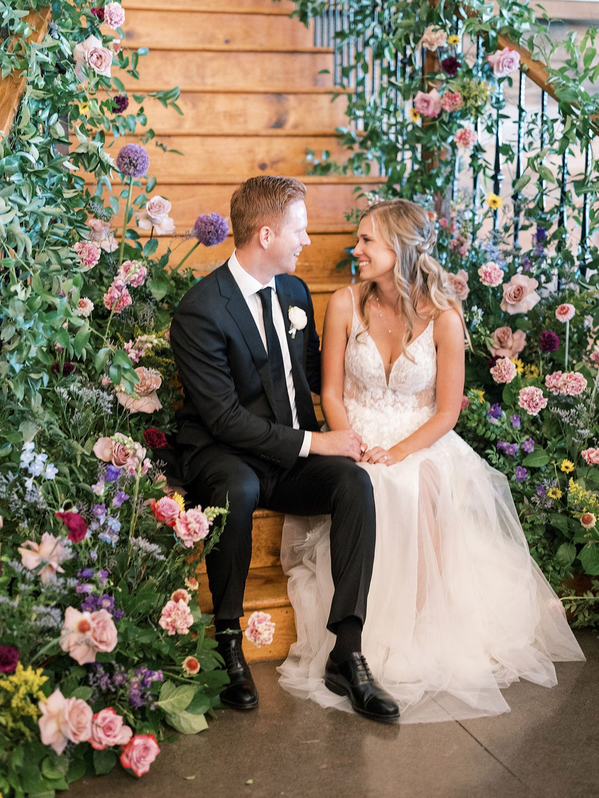 Bride and groom sitting on stairs with lush organic wildflower on stairs by Colorado wedding planner Shannon rose events