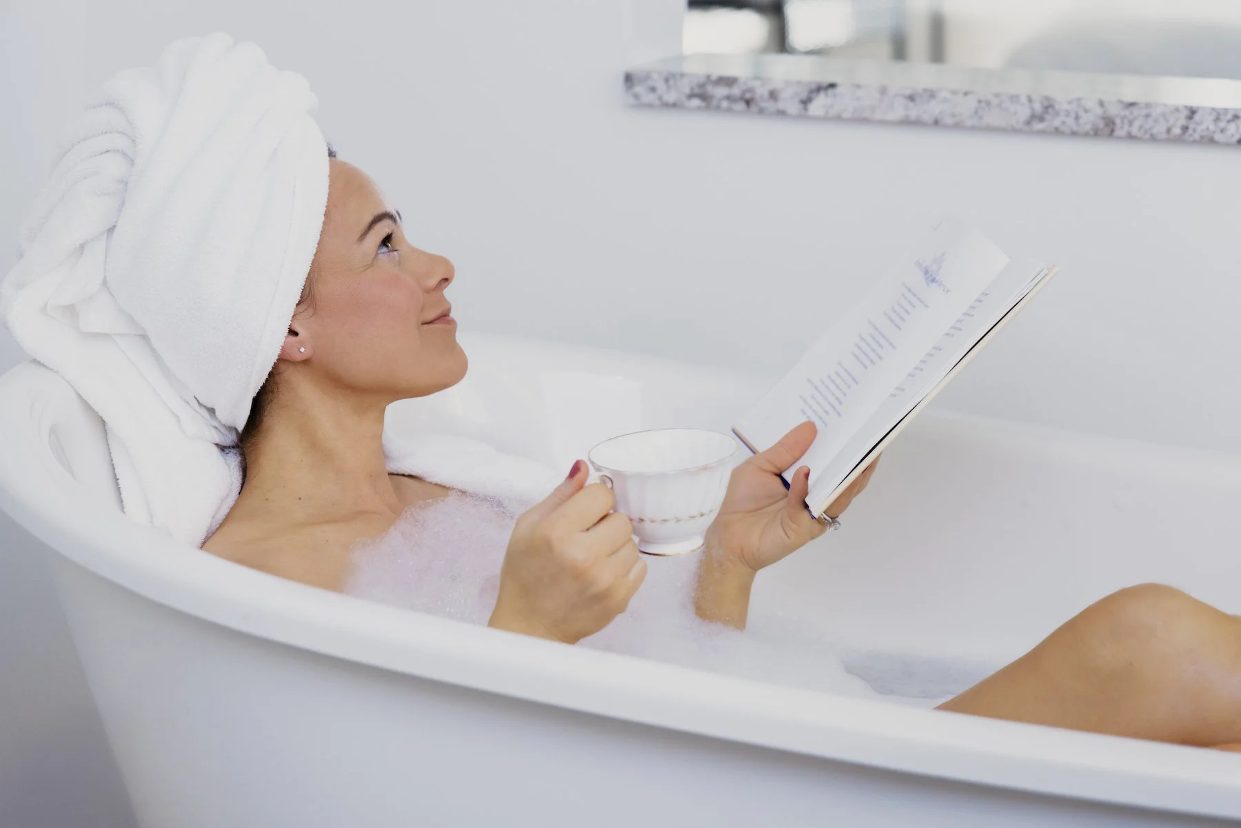 larissa carlson in bathtub with tea and book