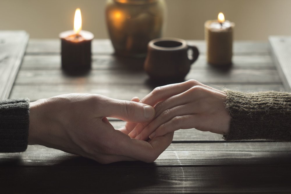 couple holding hands on table with lit candles.jpeg