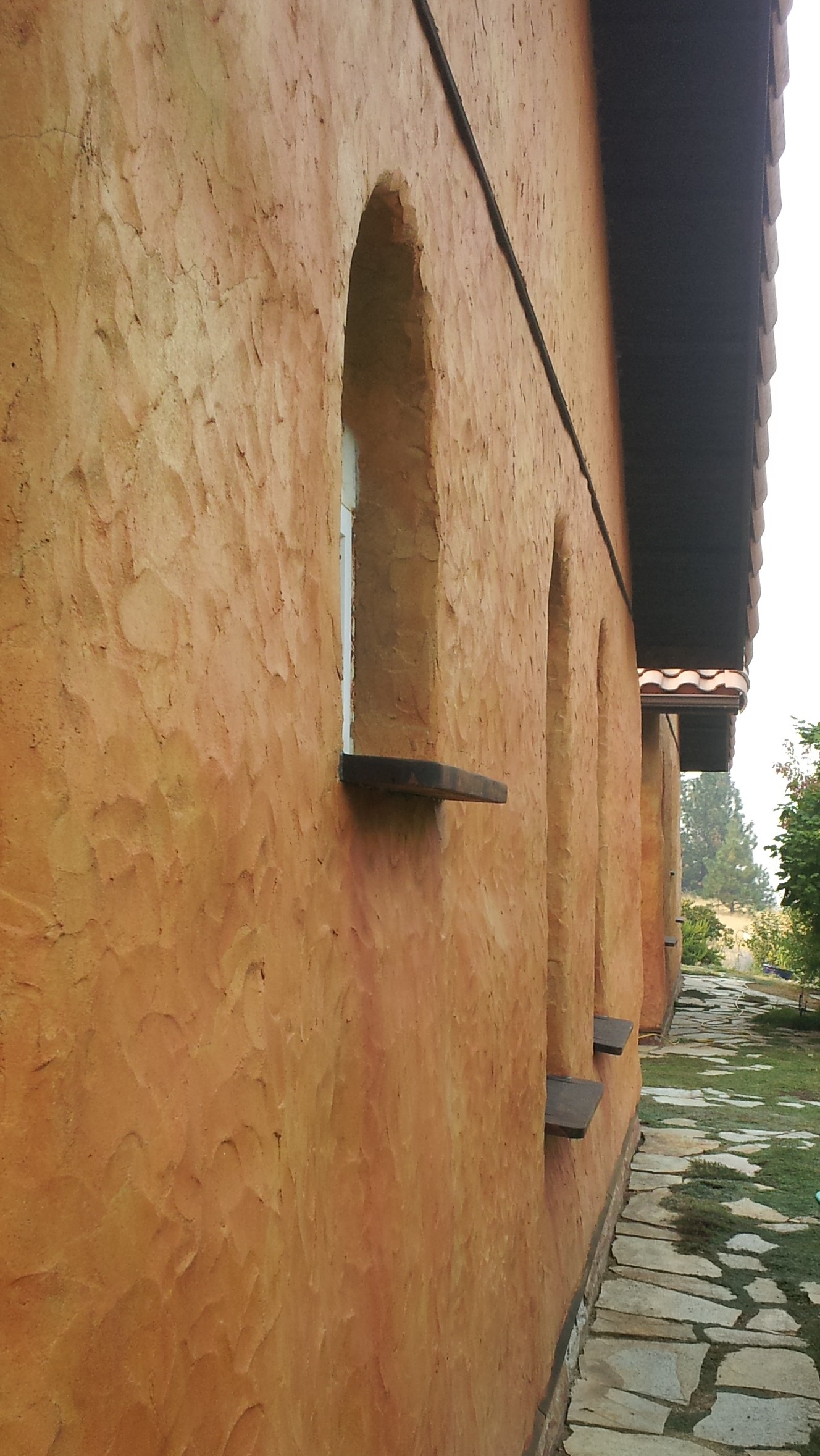  Cedar window sills extend well beyond wall plane. &nbsp;Ferrous sulfate wash over lime-cement plaster produces mottled yellow-orange color. 