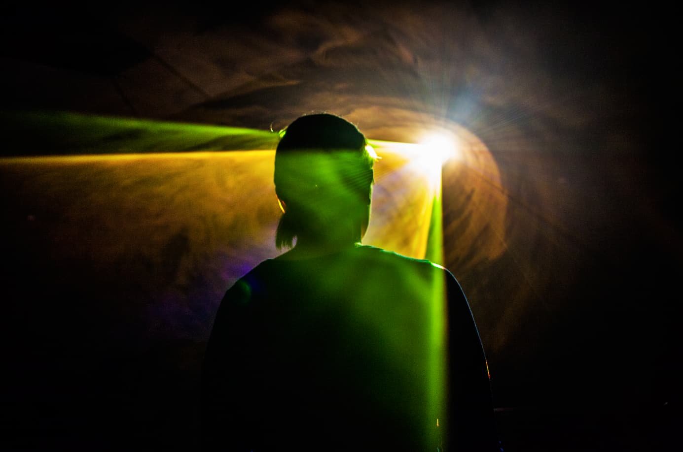 A generative light beam shining against a visitor, standing in an ever-changing experience of nature.