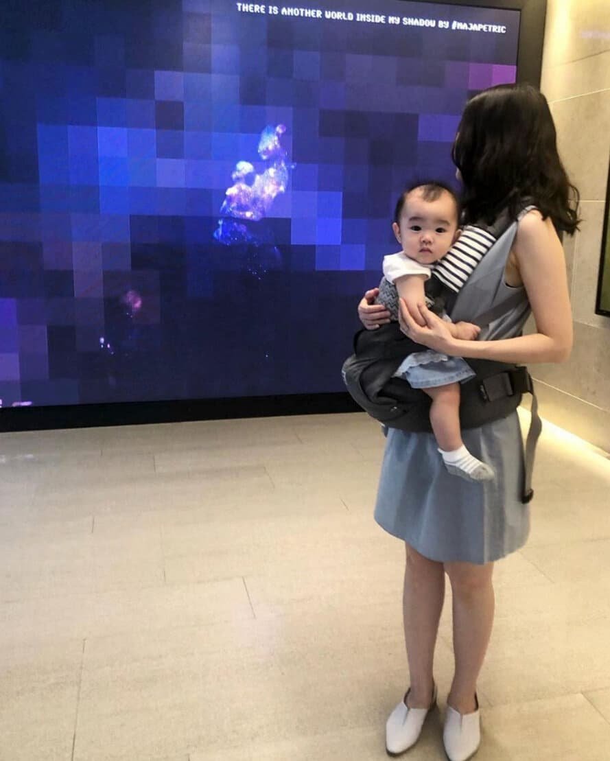 A mother and child experiencing their pixelated shadows projected onto the screen. 