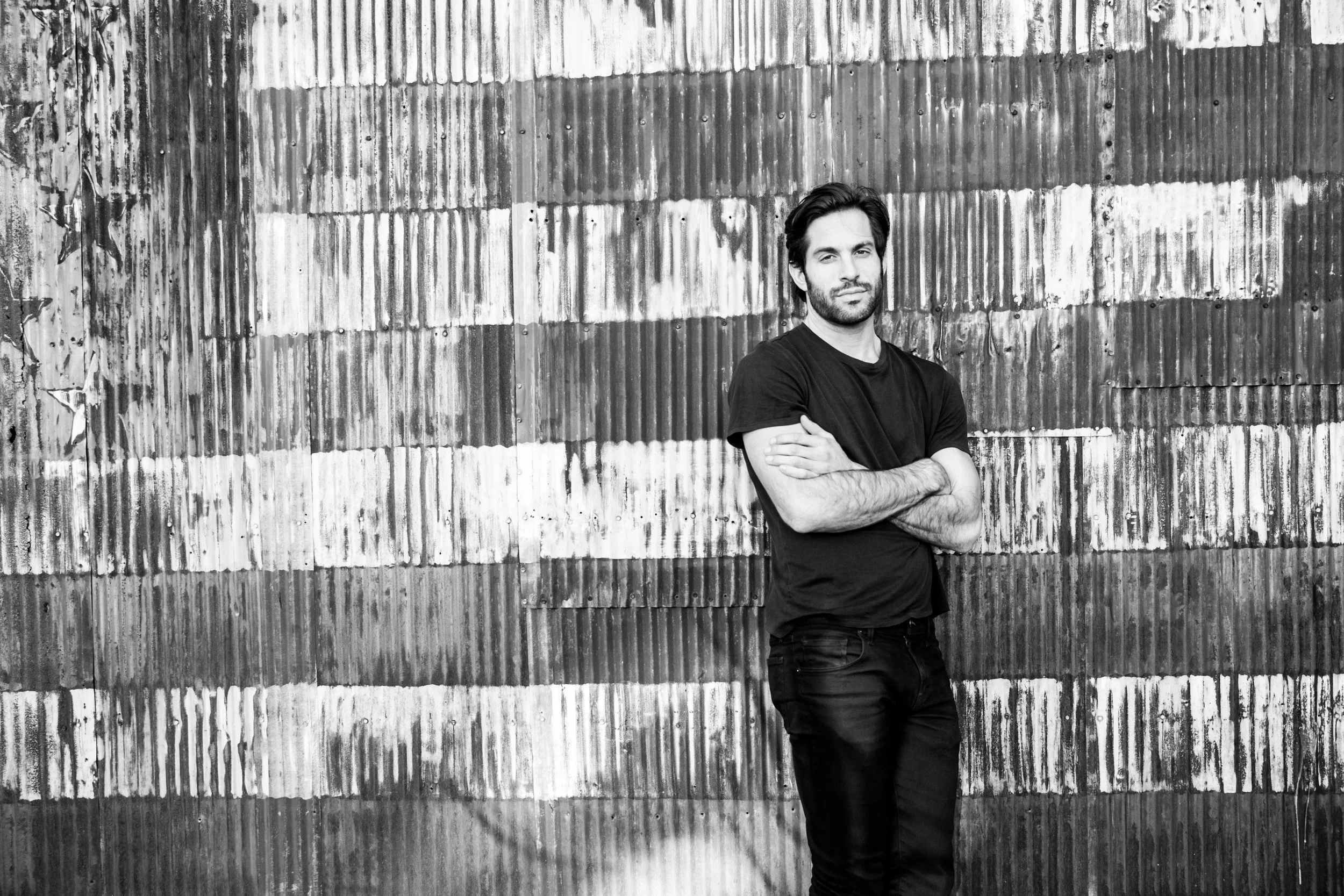 Black and white photo of Alex Regen standing in front of an American flag wall.